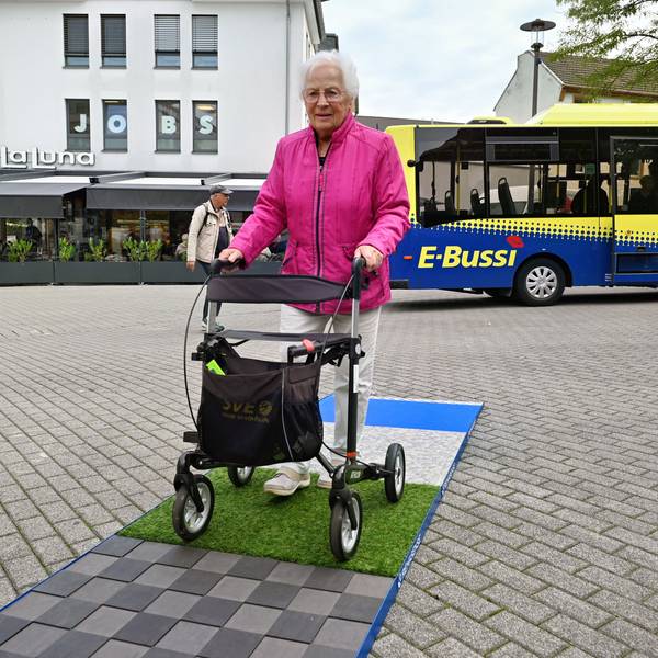 Eine Frau schiebt einen Rollator über verschiedene Beläge.