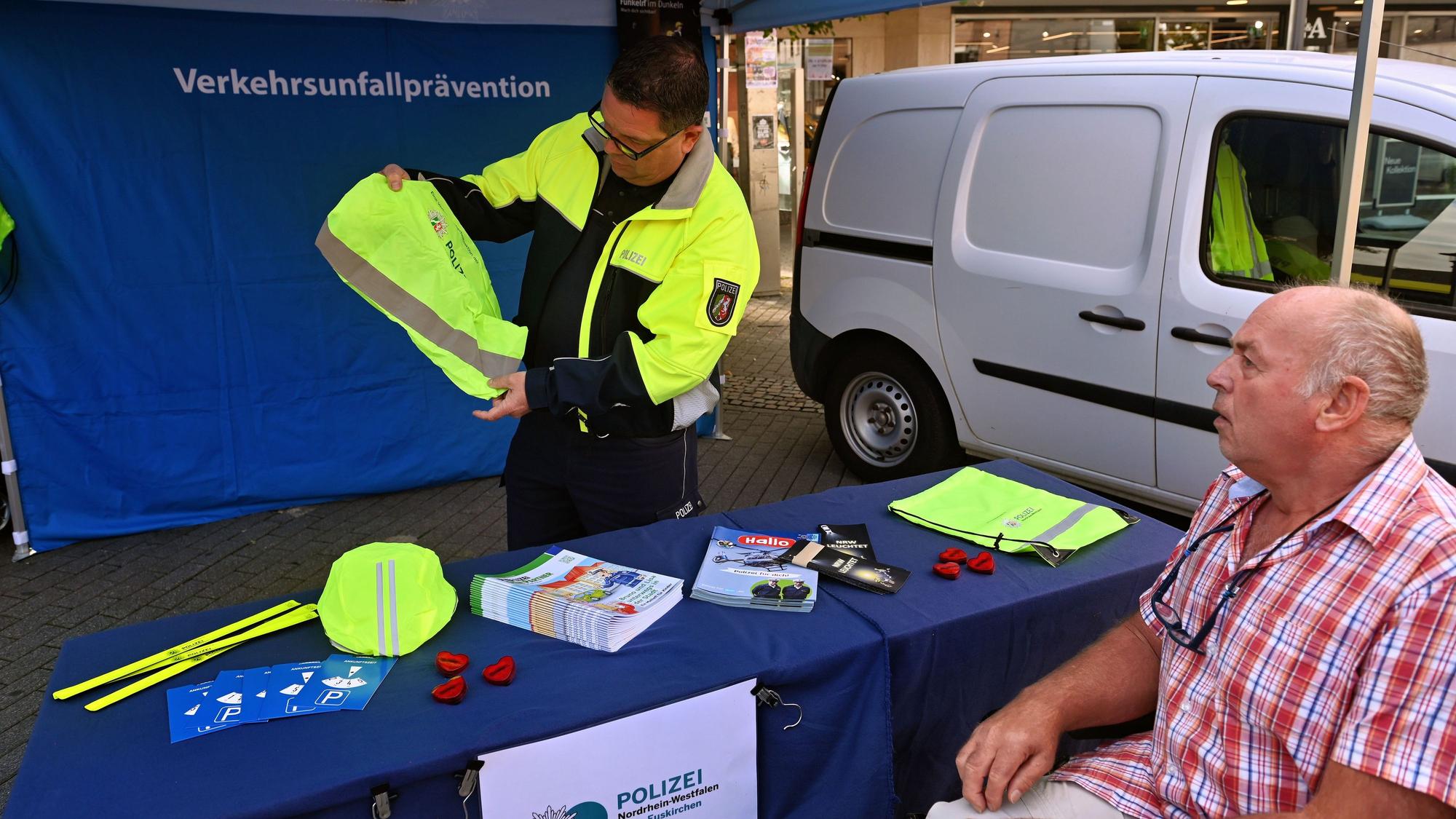Ein Polizist zeigt einem Mann im Rollstuhl reflektierende Ausrüstungsgegenstände.