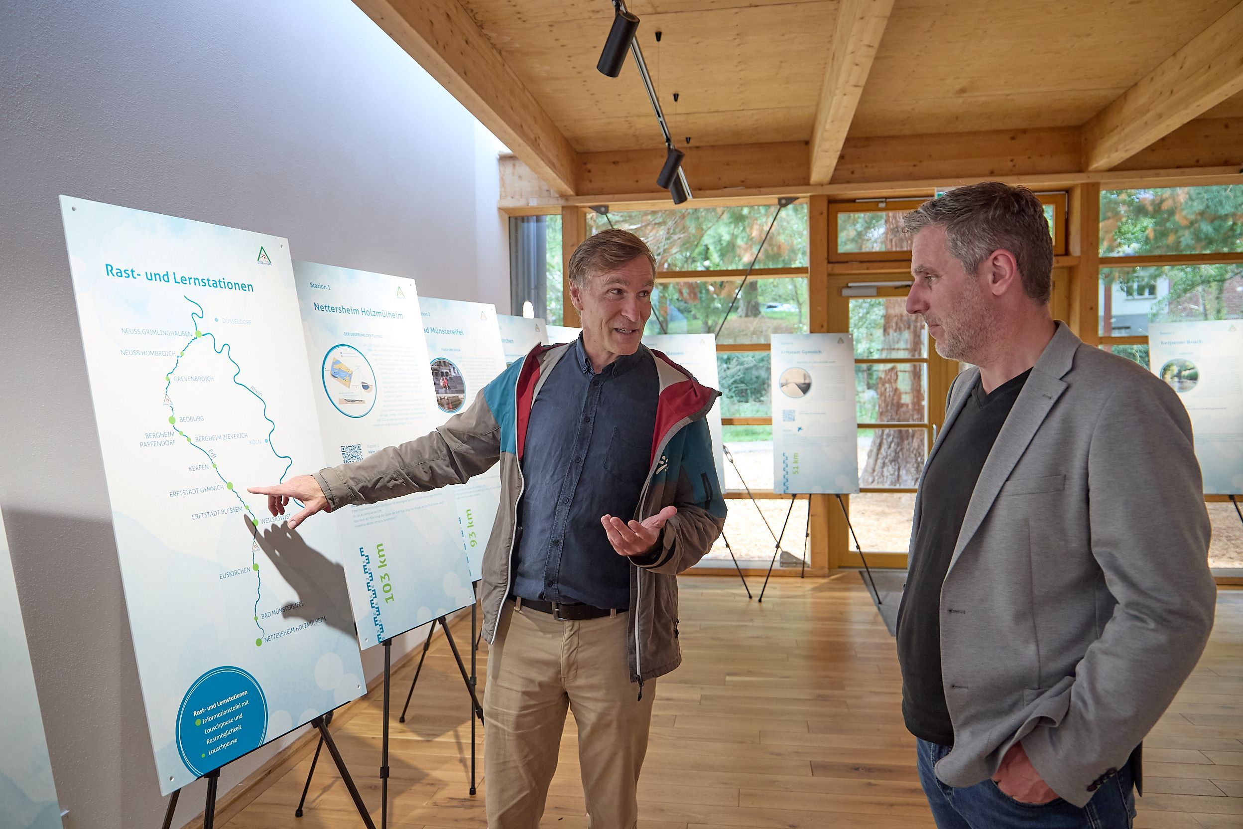 Zwei Männer stehen im Naturzentrum Nettersheim an Infotafeln und unterhalten sich.