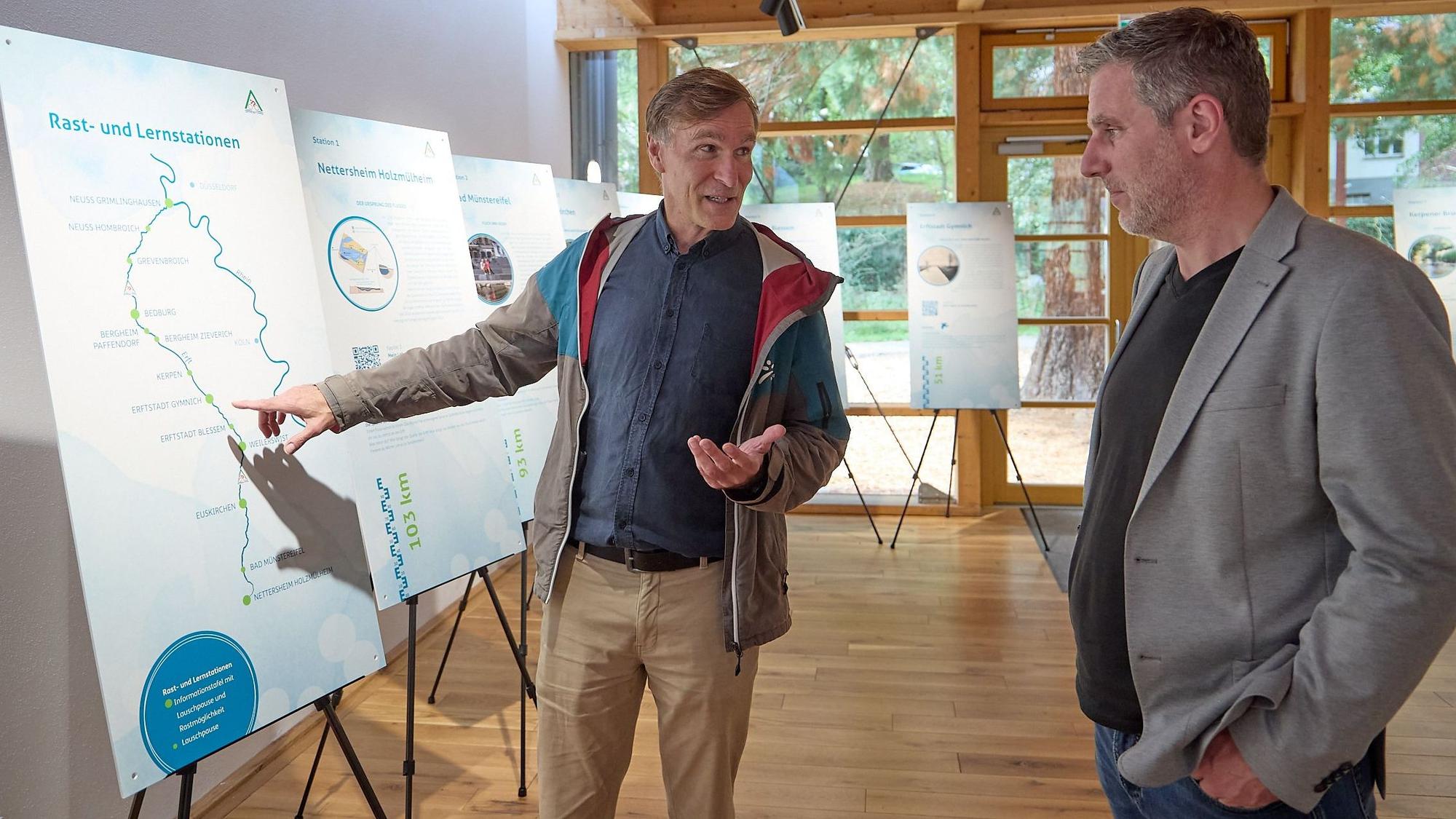 Zwei Männer stehen im Naturzentrum Nettersheim an Infotafeln und unterhalten sich.