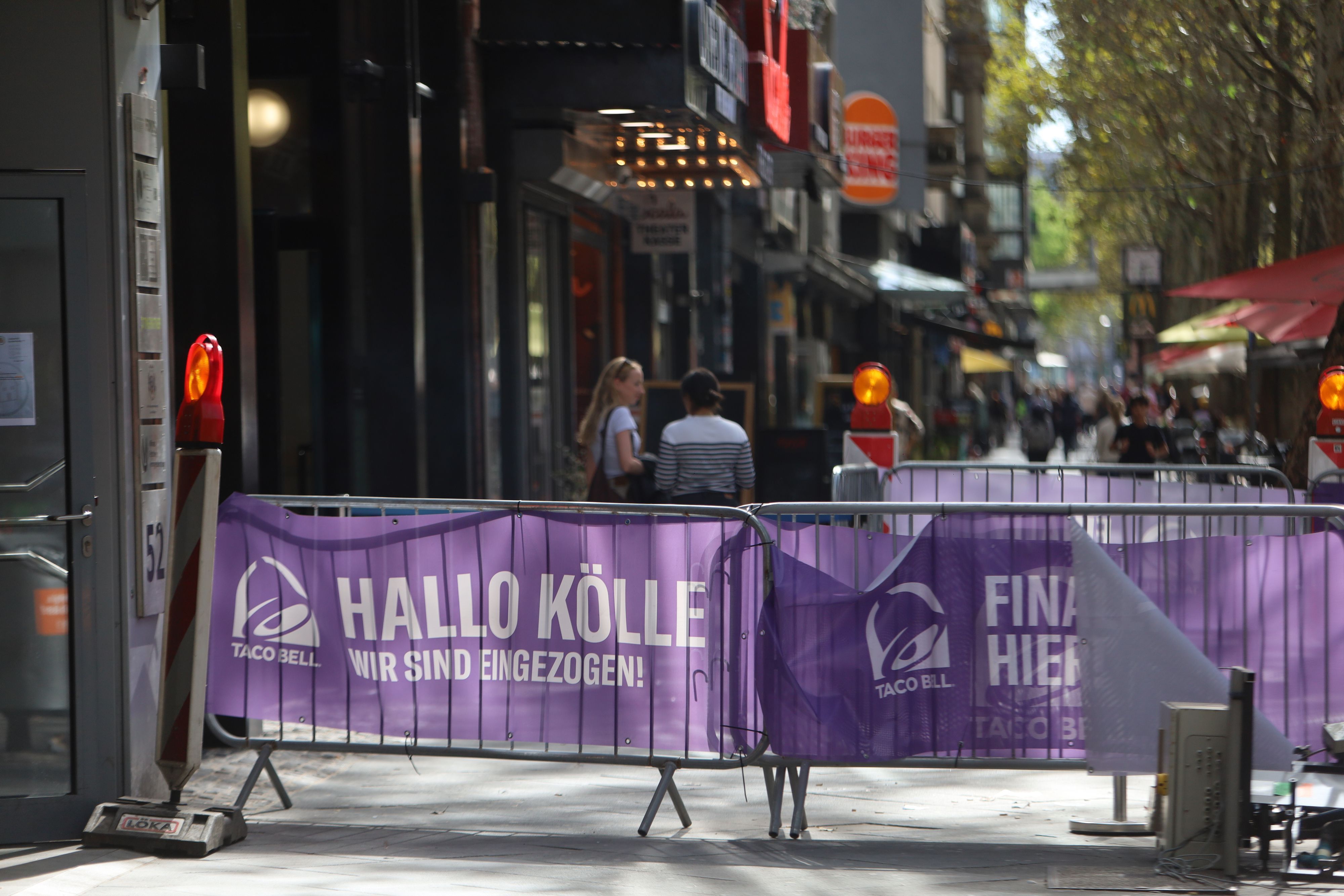 Auf Absperrgittern vor der neuen Filiale von Taco Bell in Köln steht: „Hallo Kölle, Finally Here“