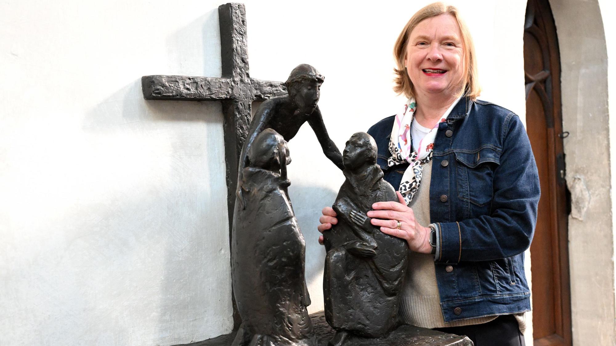 Eine blonde Frau in Jeansjacke steht an einer Bronzeplastik, die Martin Luther zeigt.