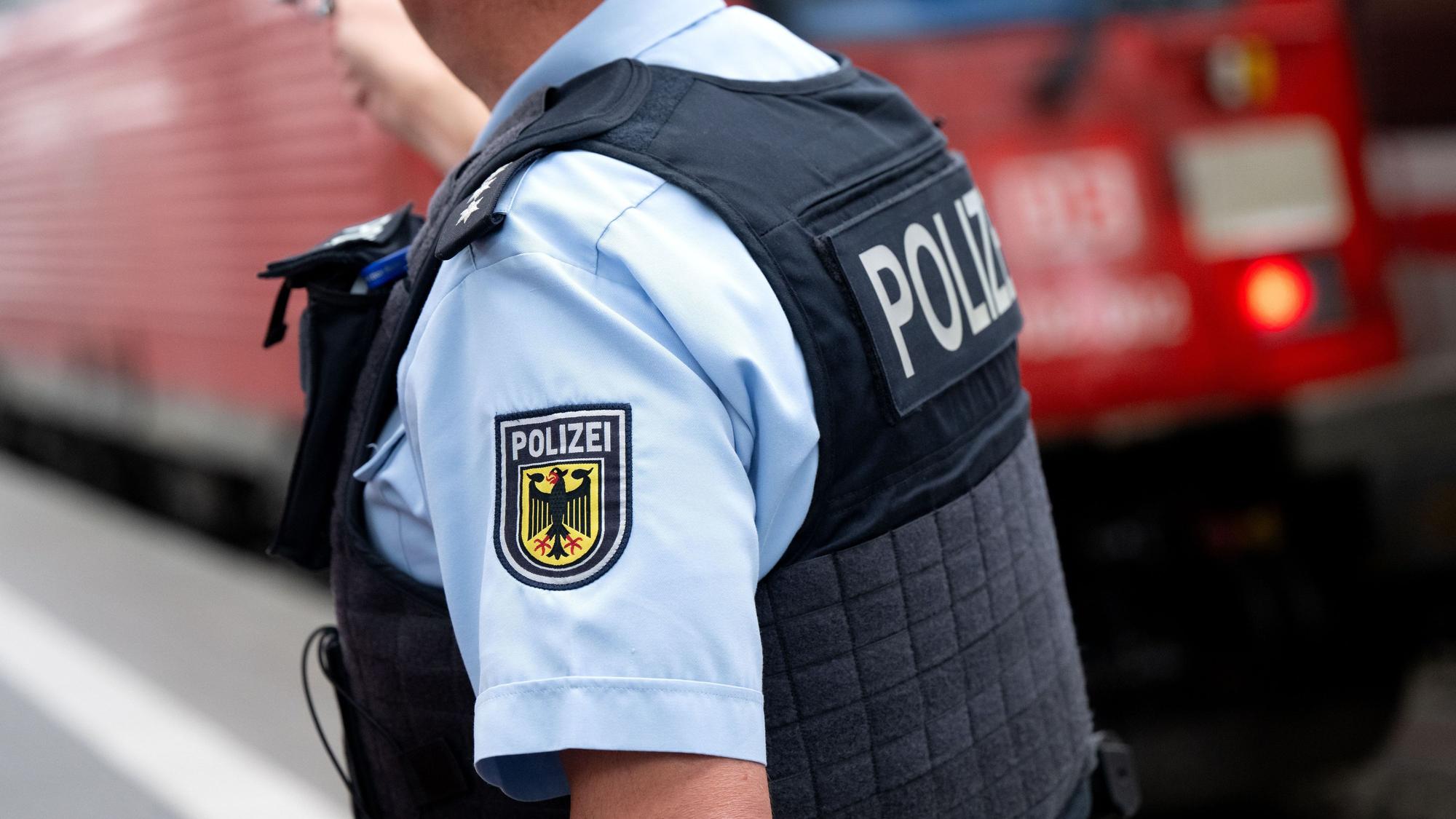 Ein Bundespolizist steht an einem Bahnsteig vor einem Zug der Deutschen Bahn.