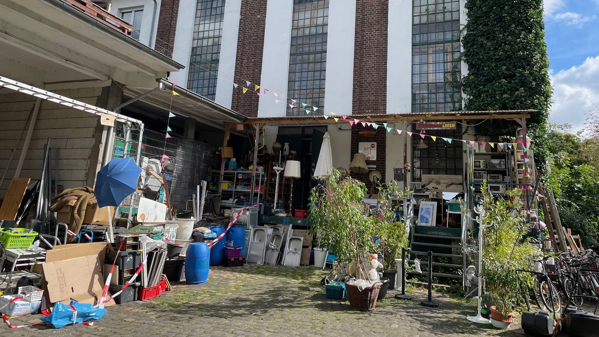 Vor einem Gebäude ist ein Hof mit viel Zeug, eine Wimpelkette spannt sich über dem Gelände.