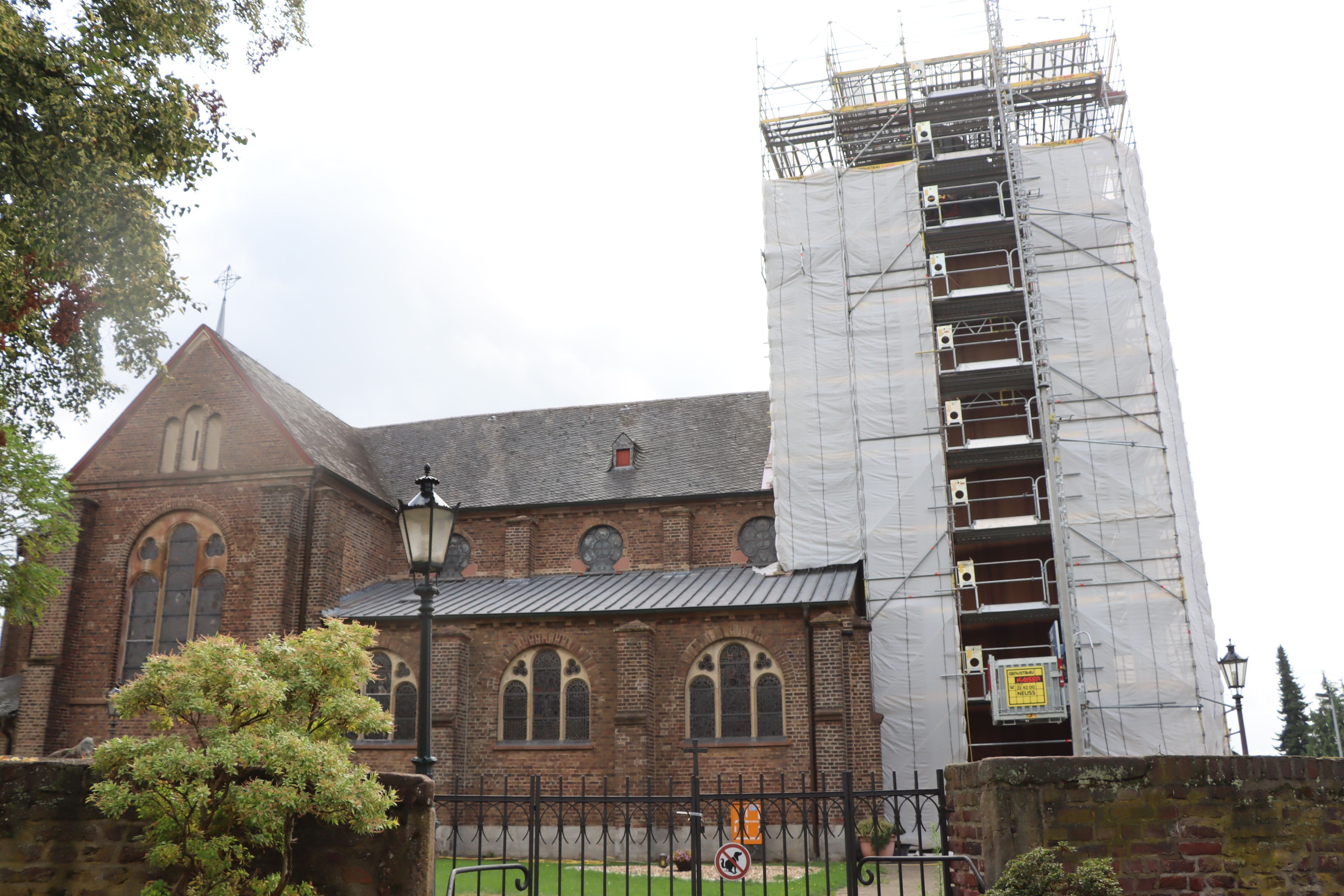Das Bild zeigt eine Kirche, deren Turm eingerüstet ist.