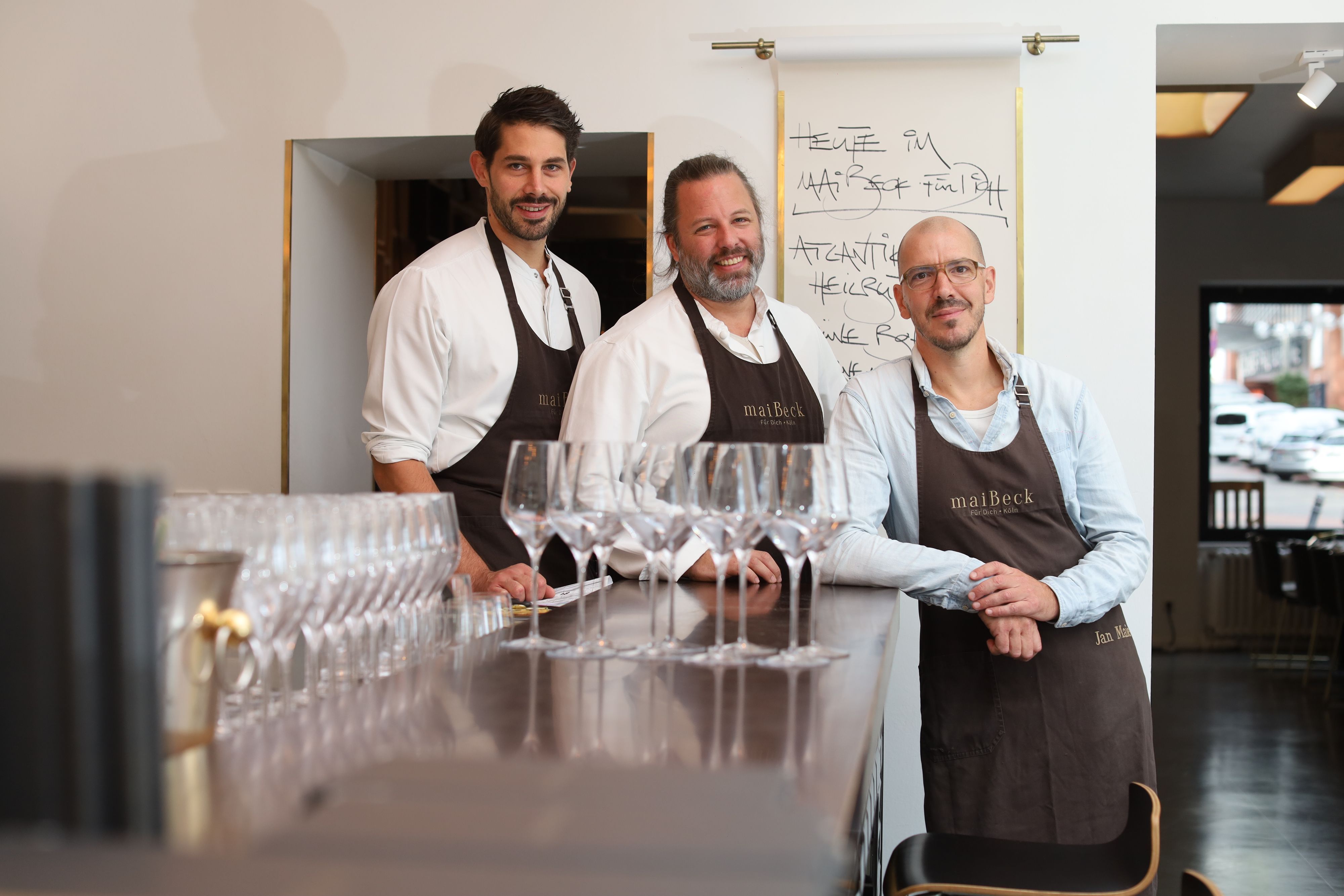 Küchenchef Johannes Adler und die Maibeck-Chefs Tobias Becker und Jan Maierstehen an der Theke des Restaurants