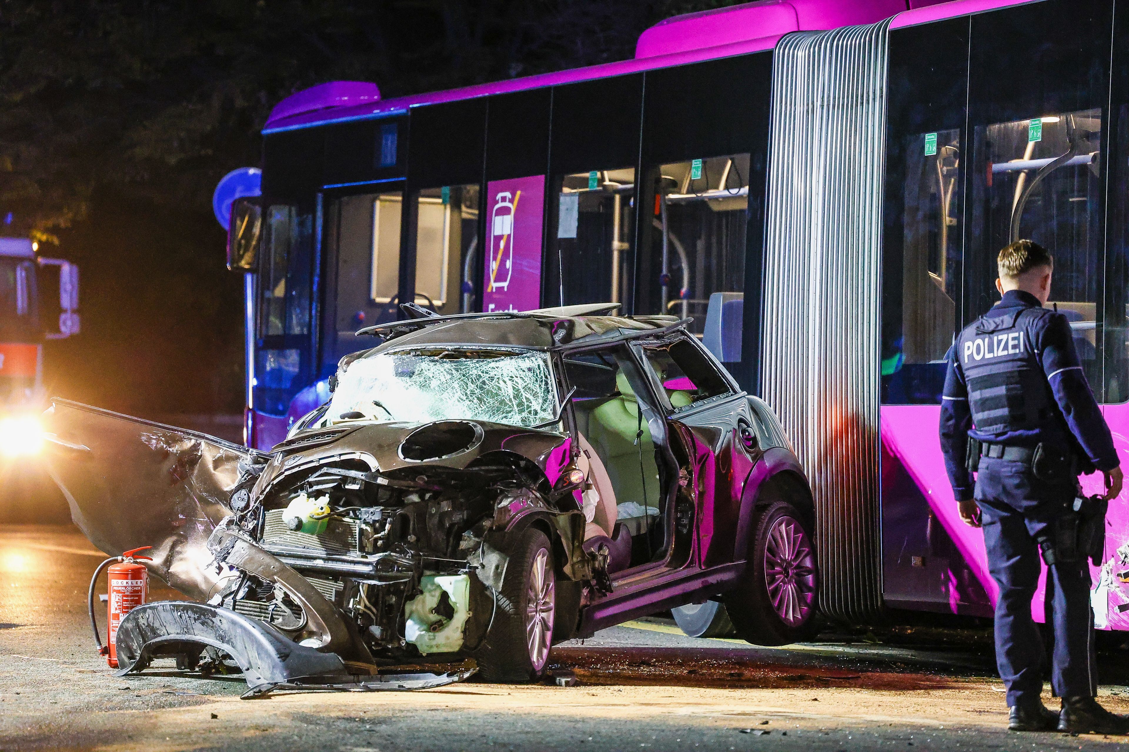 Ein Autowrack steht nach einem Unfall neben einem Bus. Bei einem Unfall mit Fahrerflucht in Witten sind in der Nacht vier junge Menschen schwer verletzt worden. Der Polizei zufolge übersah ein bisher unbekannter Fahrer bei einem Überholmanöver augenscheinlich einen entgegenkommenden Linienbus. Er scherte nach rechts aus und prallte so gegen ein weiteres Auto, das daraufhin frontal gegen den Linienbus geschleudert wurde.