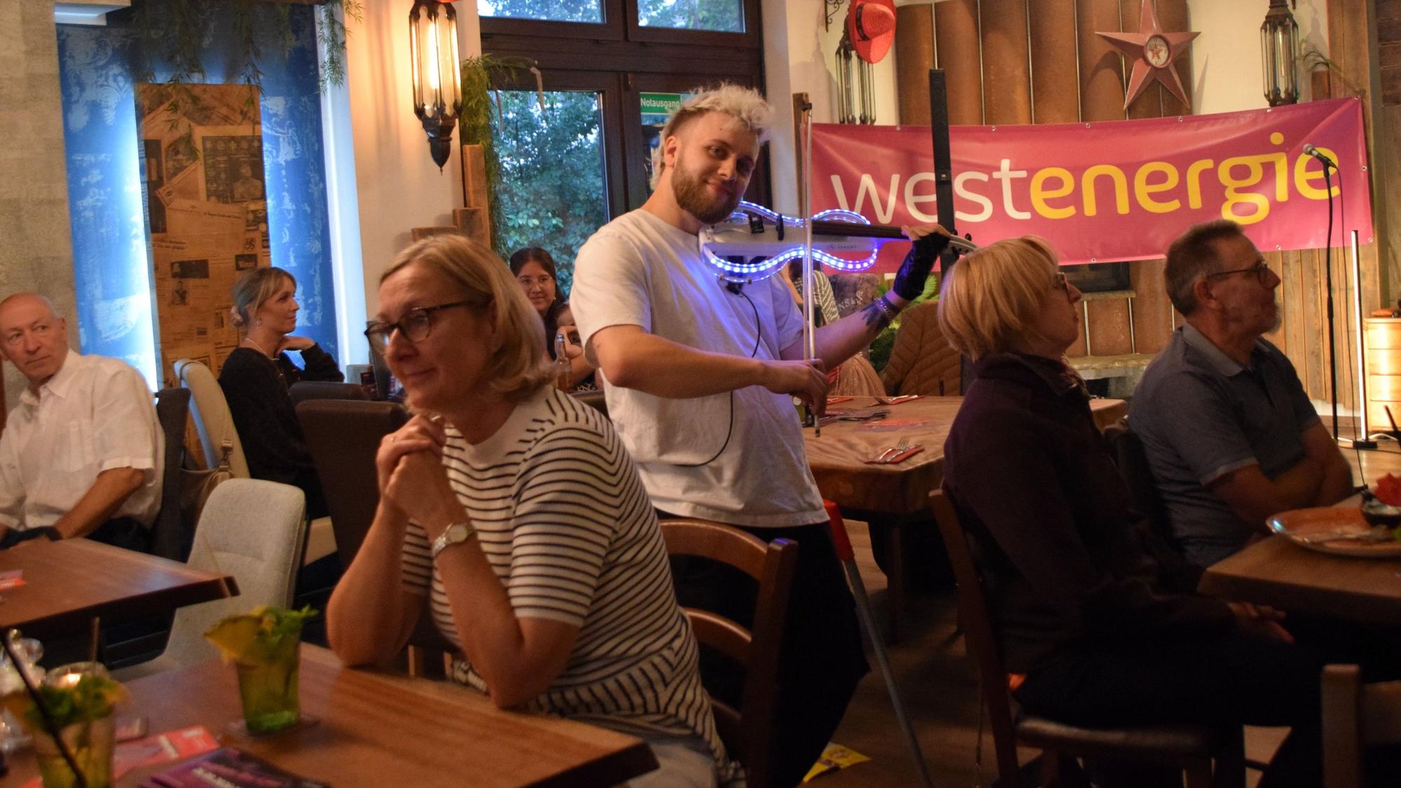 Ein Mann spielt auf einer gläsernen und beleuchteten Geige.