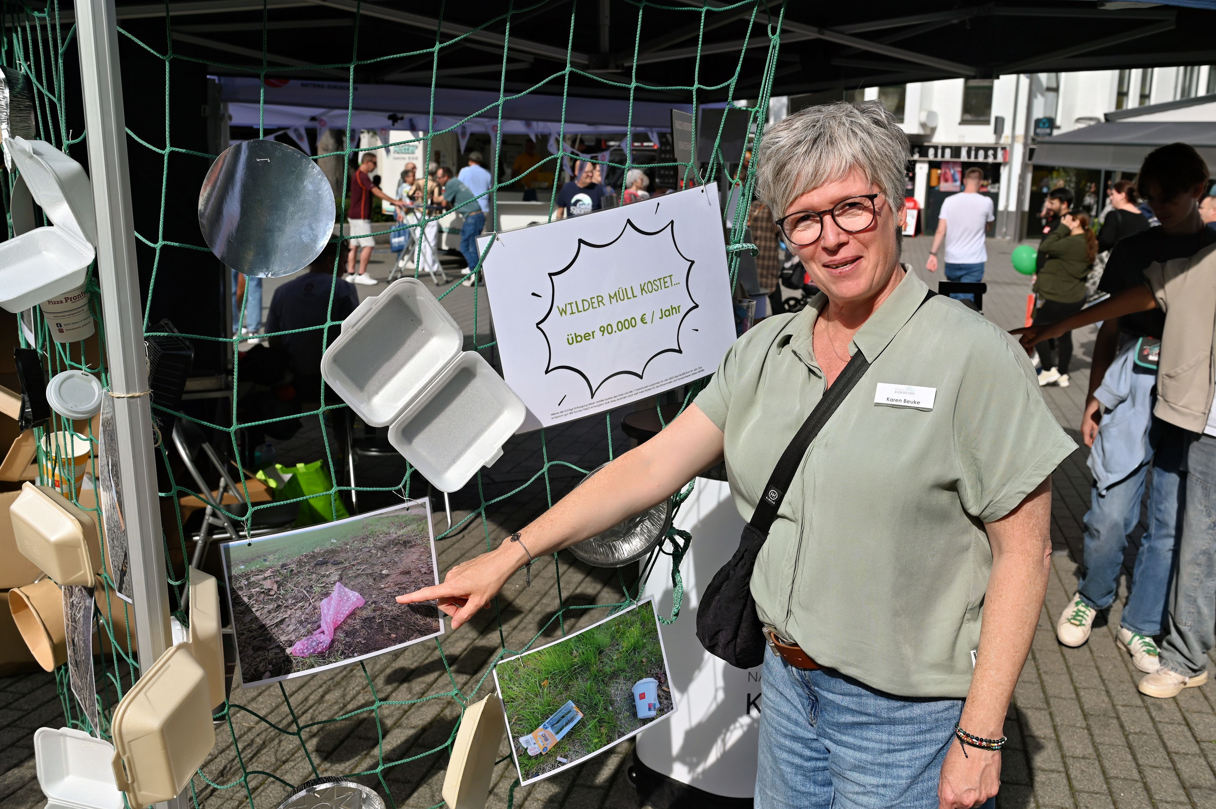 Eine Frau weist auf Fotos, um auf die Problematik des Wilden Mülls aufmerksam zu machen.