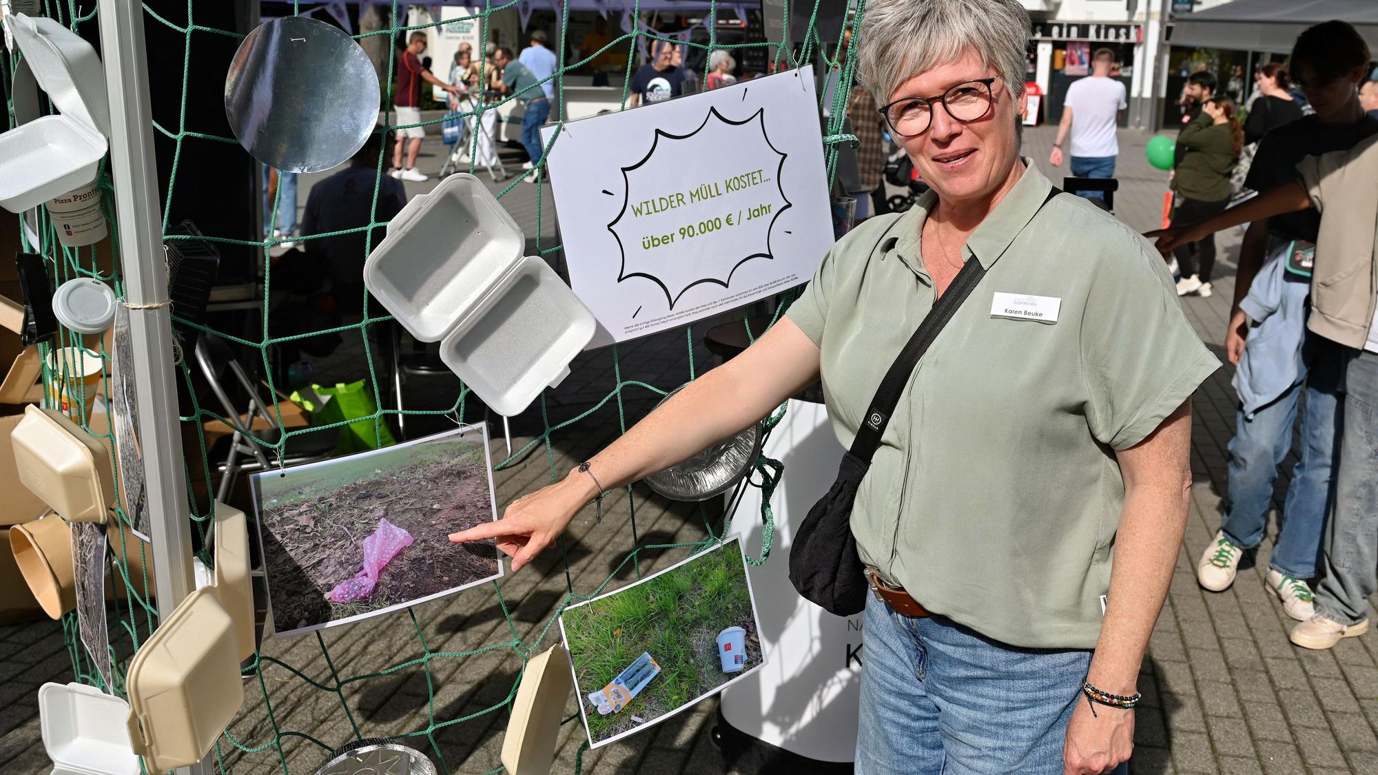 Eine Frau weist auf Fotos, um auf die Problematik des Wilden Mülls aufmerksam zu machen.
