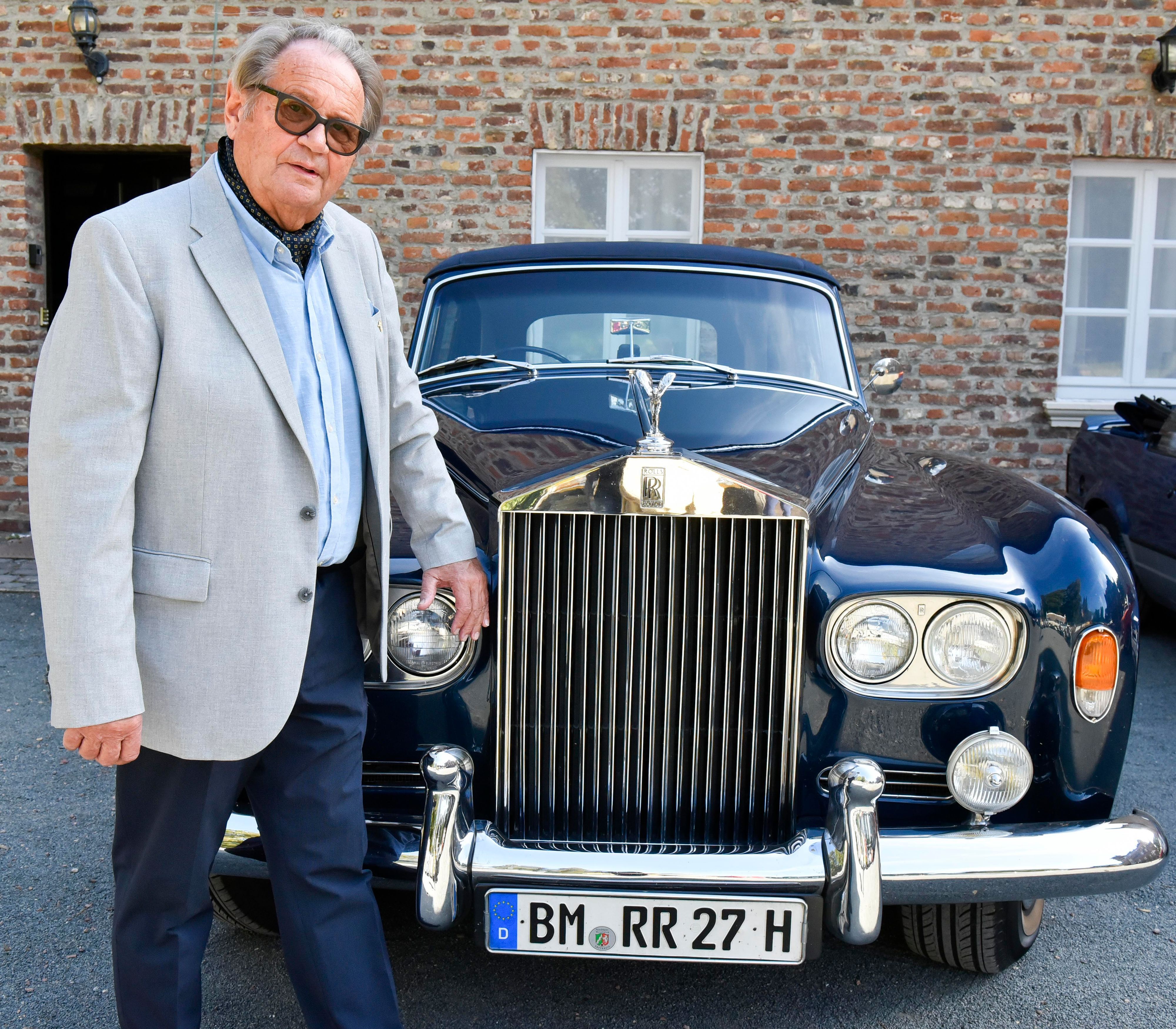 Das Bild zeigt einen Mann mit seinem blauen Rolls Royce Kombi Silver Shadow III.