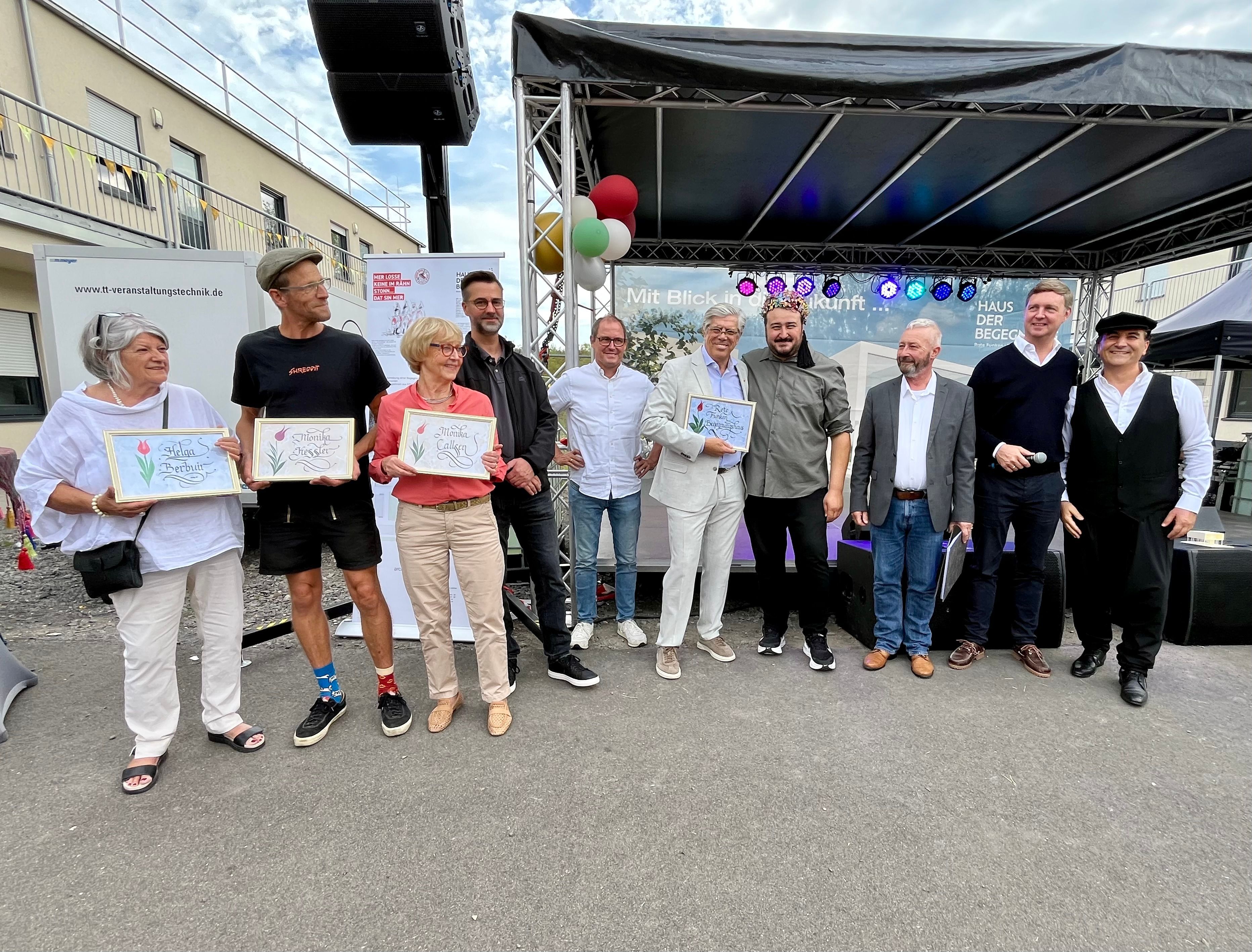 Das Bild zeigt Personen von der Flüchtlingshilfe, der Kirchengemeinden, der Stadt Erftstadt sowie der Roten Funken auf der Bühne.