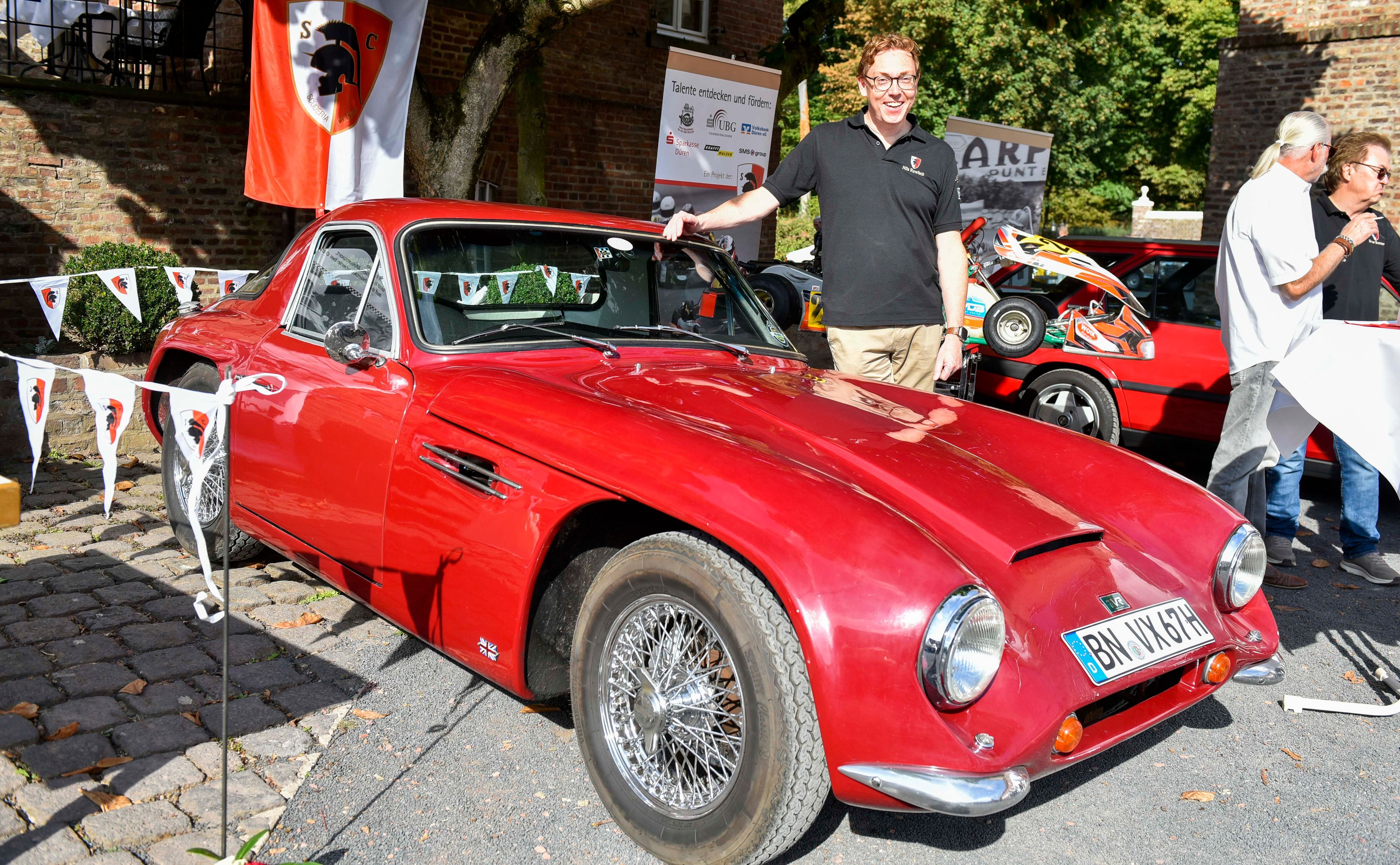Das Bild zeigt einen Mann mit seinem roten TVR, Baujahr 1967, der einmal Roger Moore gehört haben soll.