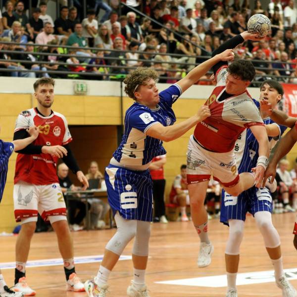 Marius Schmitz wird am Wurf von einem Gegenspieler gehindert, der Schmitz am Trikot reißt und an den Arm fasst.
