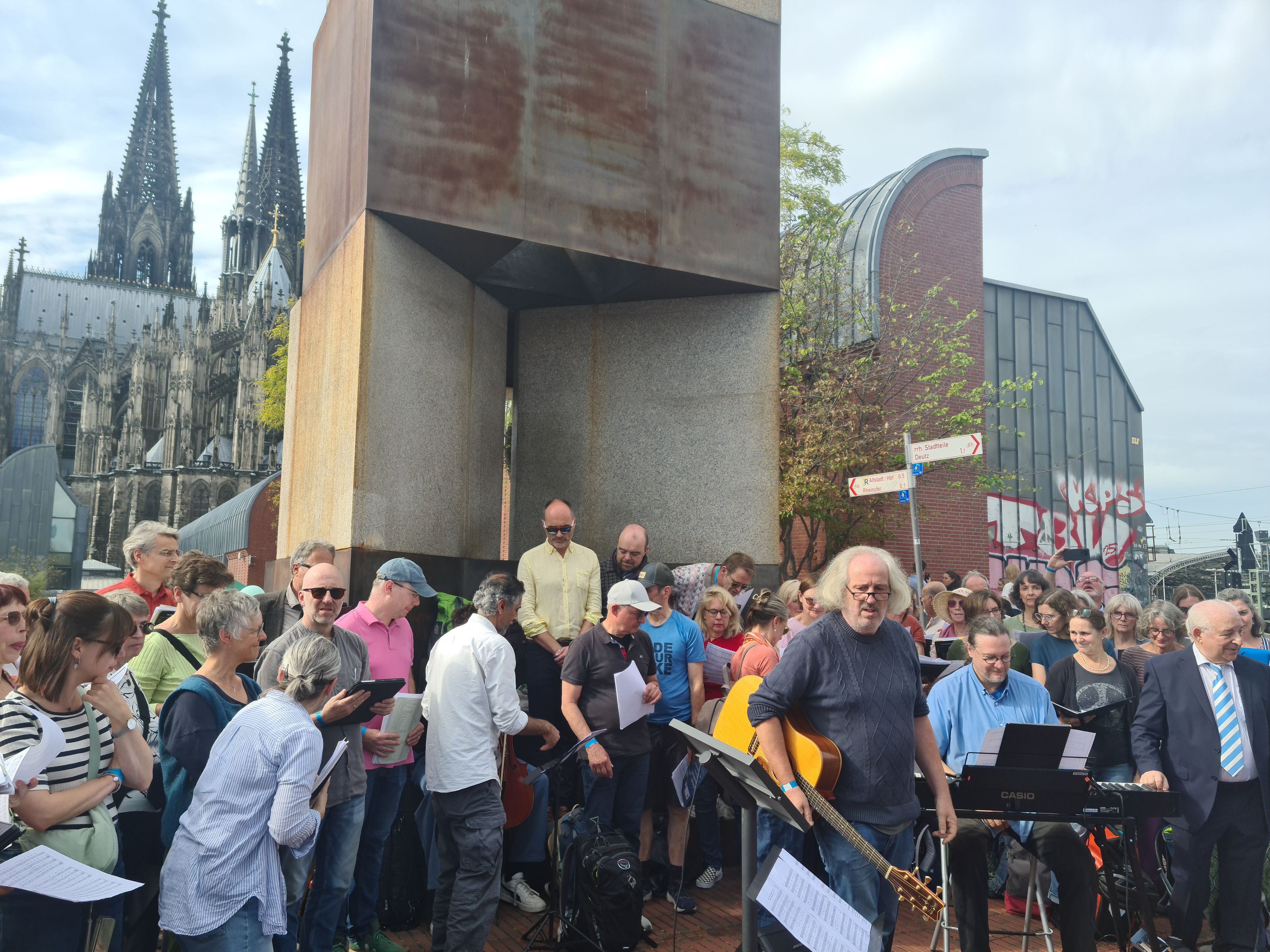 Viele Leute stehen vor einem Turm, im Hintergrund sind der Dom und das Museum Ludwig.