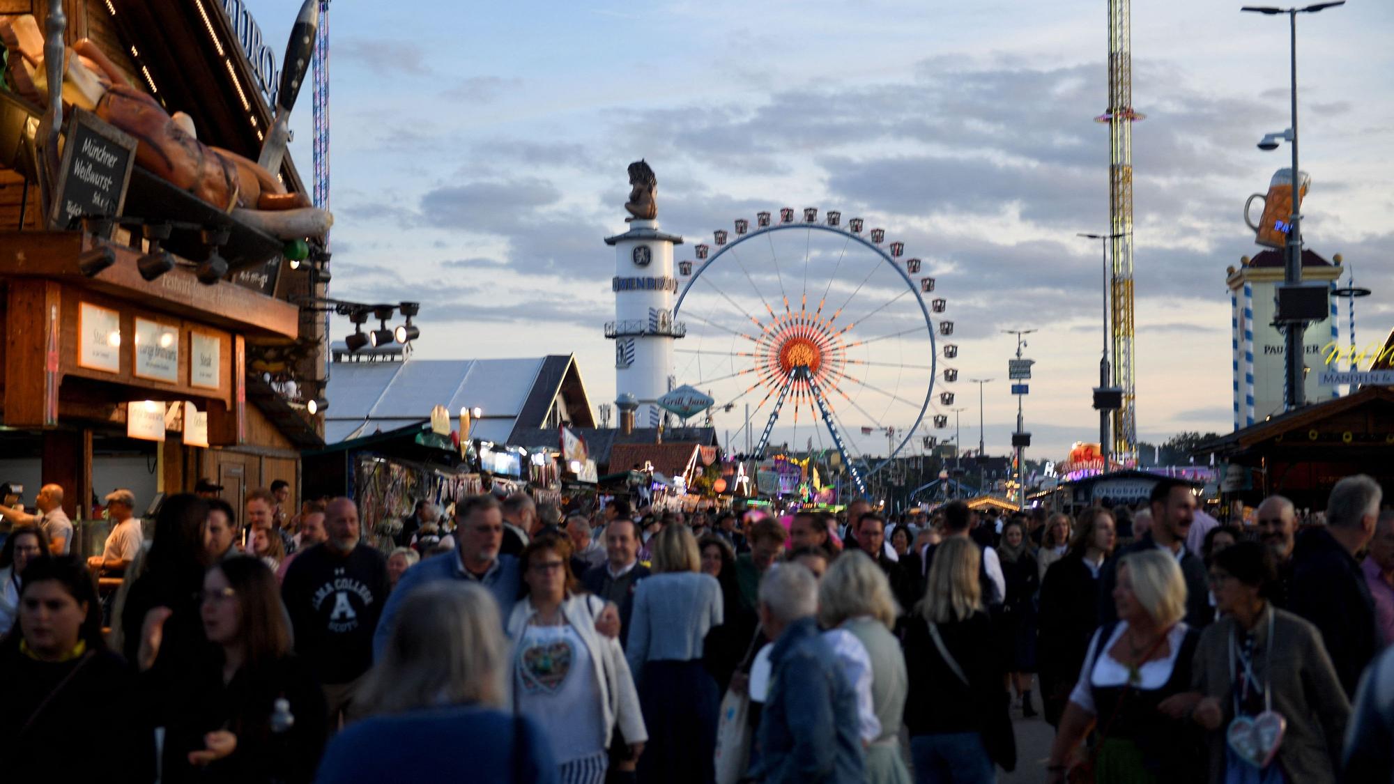 Wiesngäste gehen über das Oktoberfest.