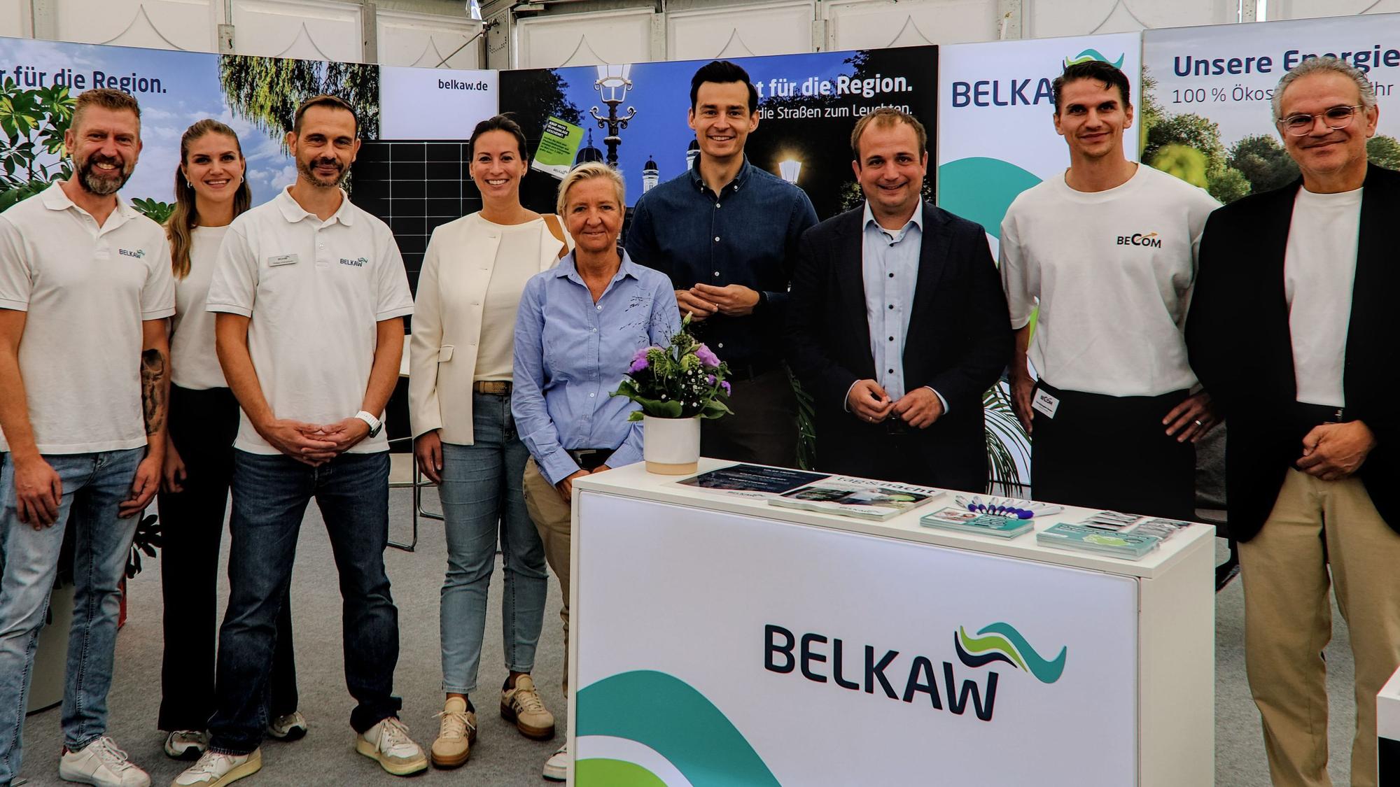 Mehrere Frauen und Männer stehen an einem Stand mit der Aufschrift Belkaw