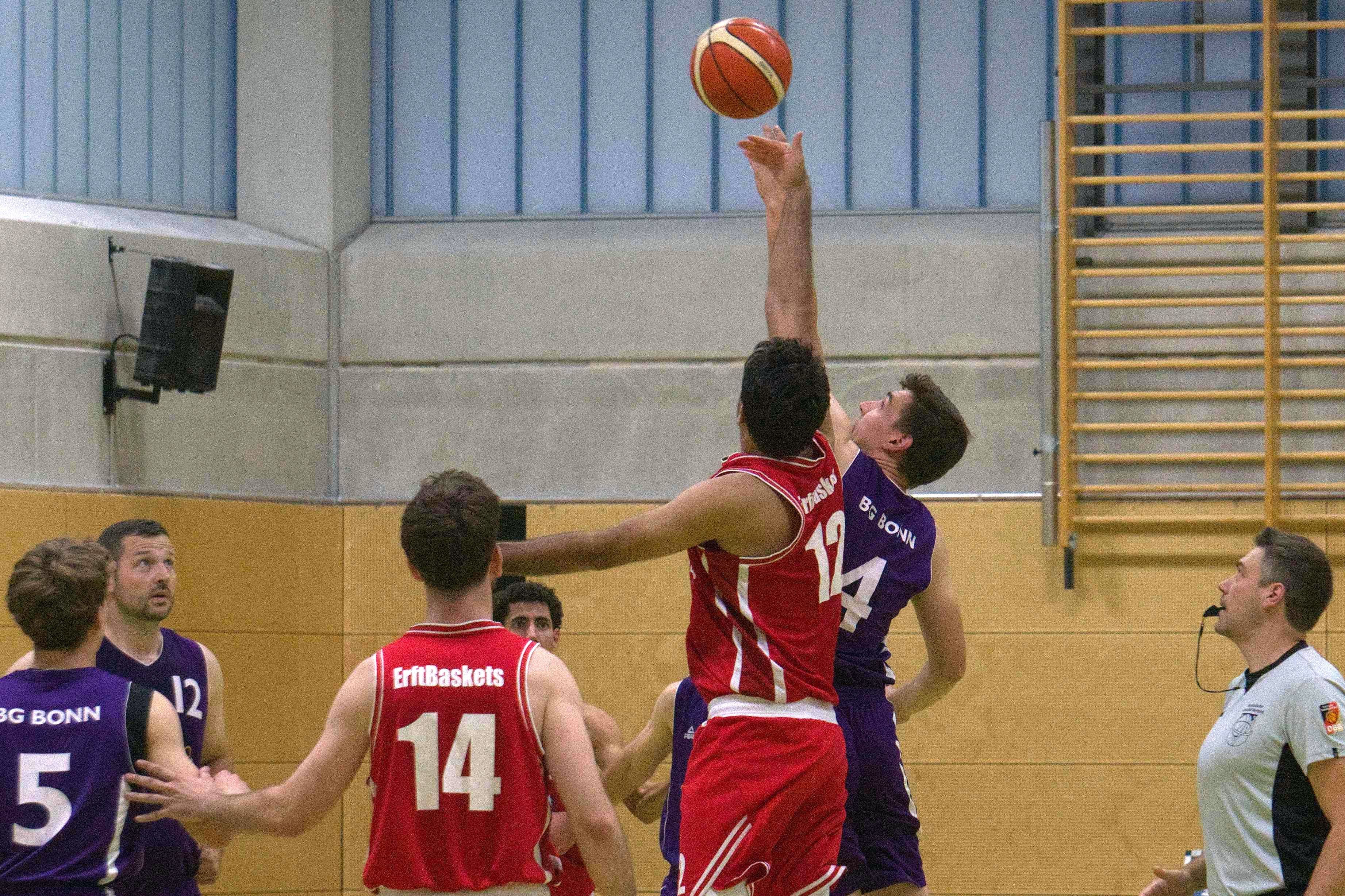Zwei Spieler kämpfen um den Ball, andere beobachten die Szene.