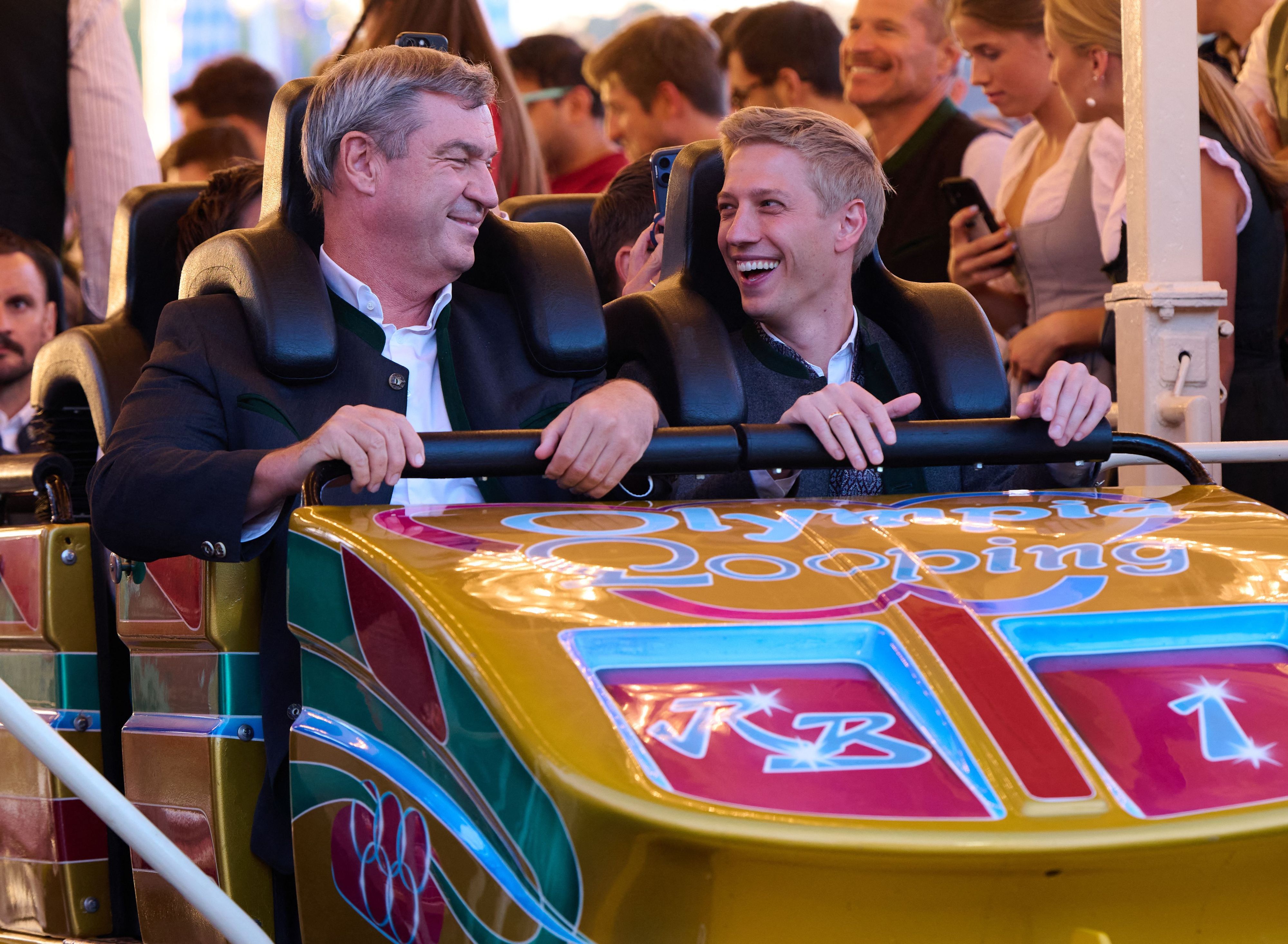 Markus Söder (CSU, l.), Ministerpräsident von Bayern, und Dominik Krause (Bündnis 90/ Die Grünen), Oberbürgermeister von München, fahren auf dem Oktoberfest zusammen mit der Achterbahn „Olympia Looping“.