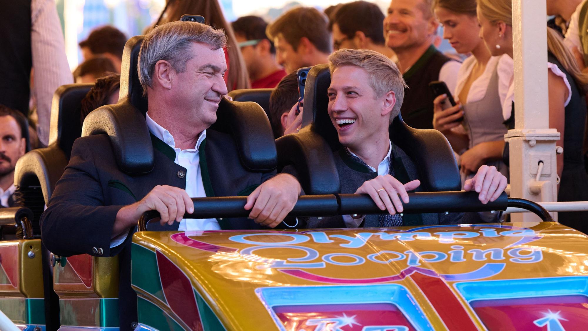 Markus Söder (CSU, l.), Ministerpräsident von Bayern, und Dominik Krause (Bündnis 90/ Die Grünen), Oberbürgermeister von München, fahren auf dem Oktoberfest zusammen mit der Achterbahn „Olympia Looping“.