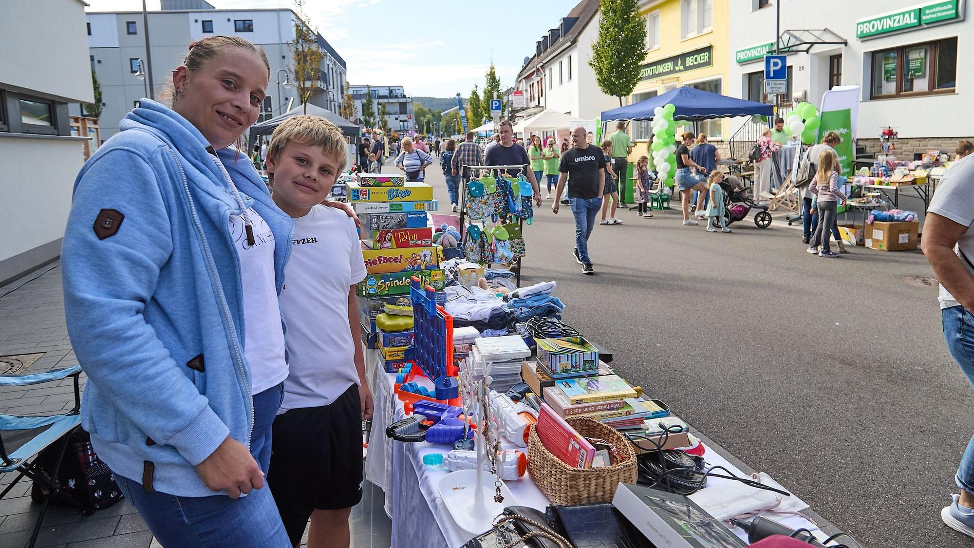 Eine Frau und ein Junge stehen vor einem Tisch mit Flohmarktsachen.