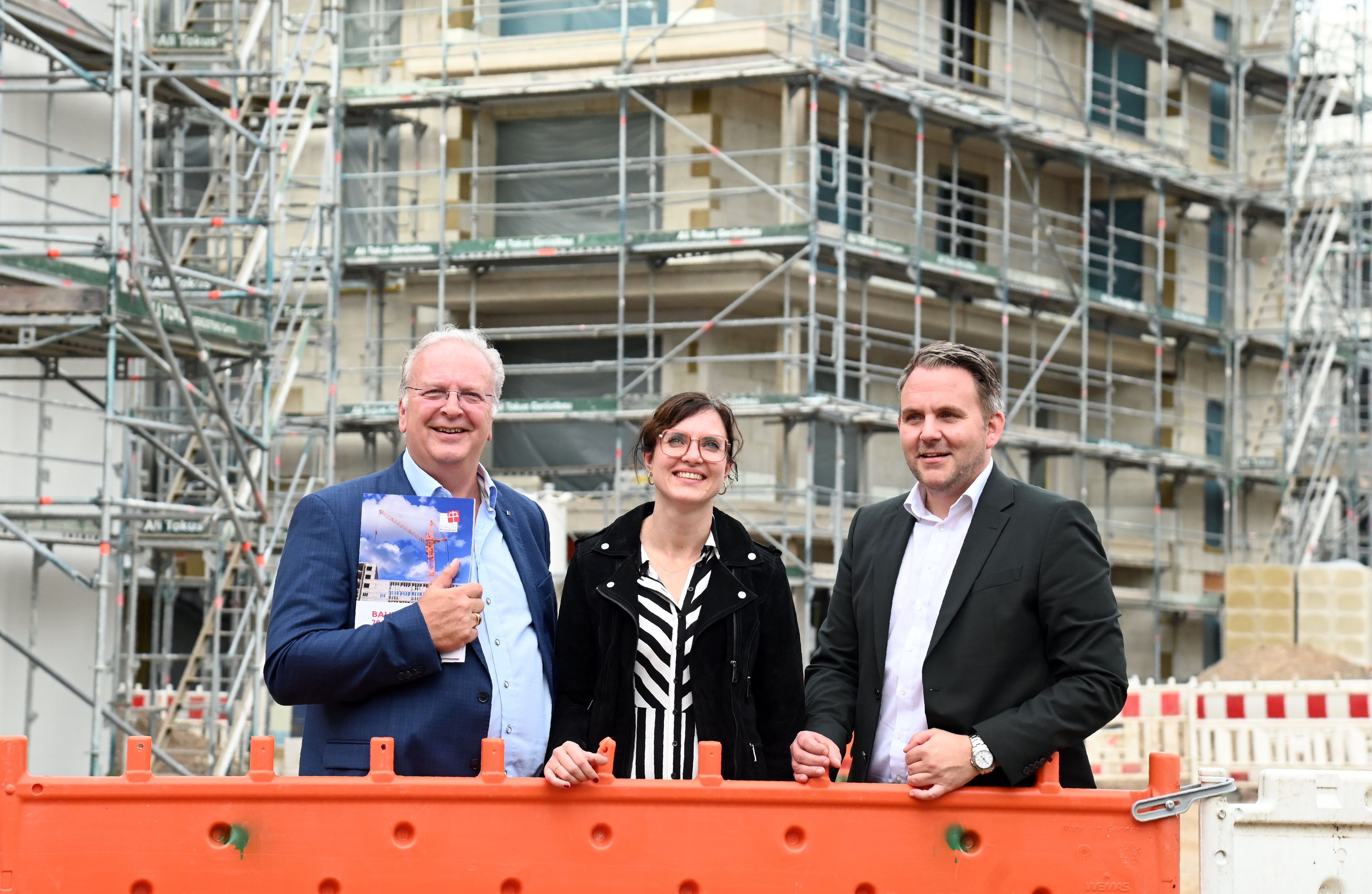 Uwe Ufer, Kirsten Neveling und Christian Potthoff stehen im Gruppenbild vor dem Rohbau.