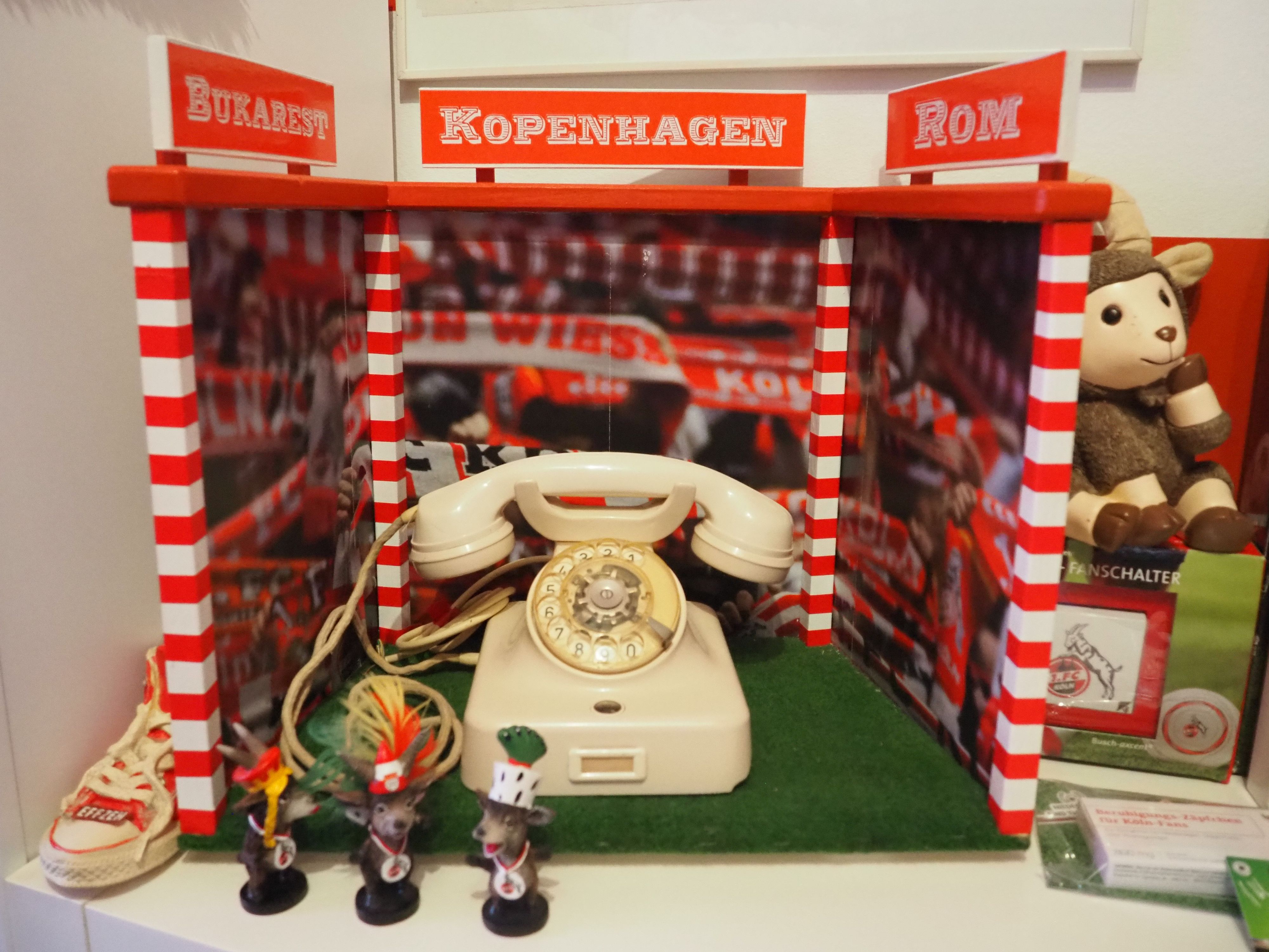 Ein Wählscheibentelefon steht zwischen rotweißen Pfosten.