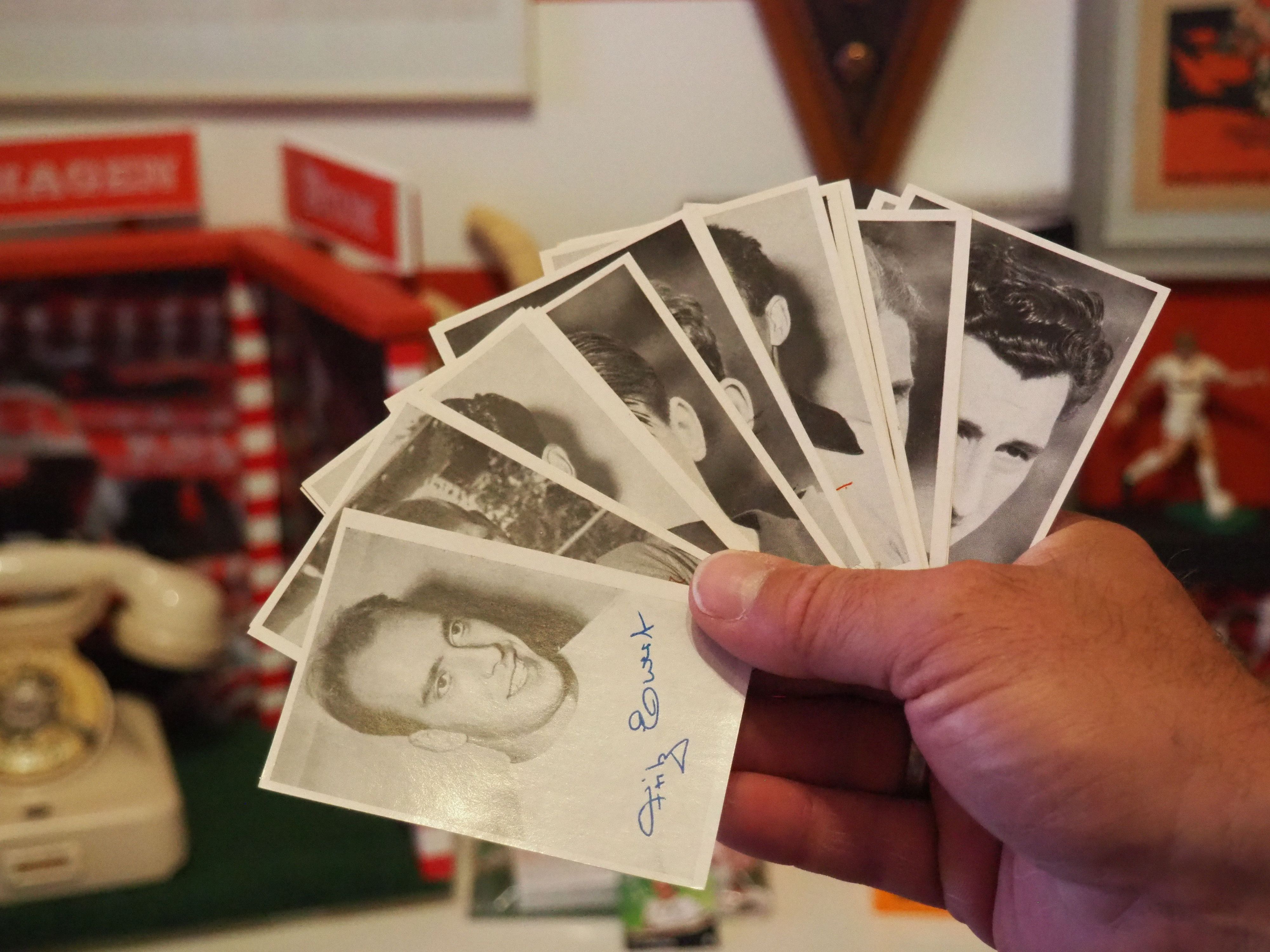 Eine Hand hält Autogrammkarten in Schwarz-Weiß, aufgefächert wie ein Kartenspiel.