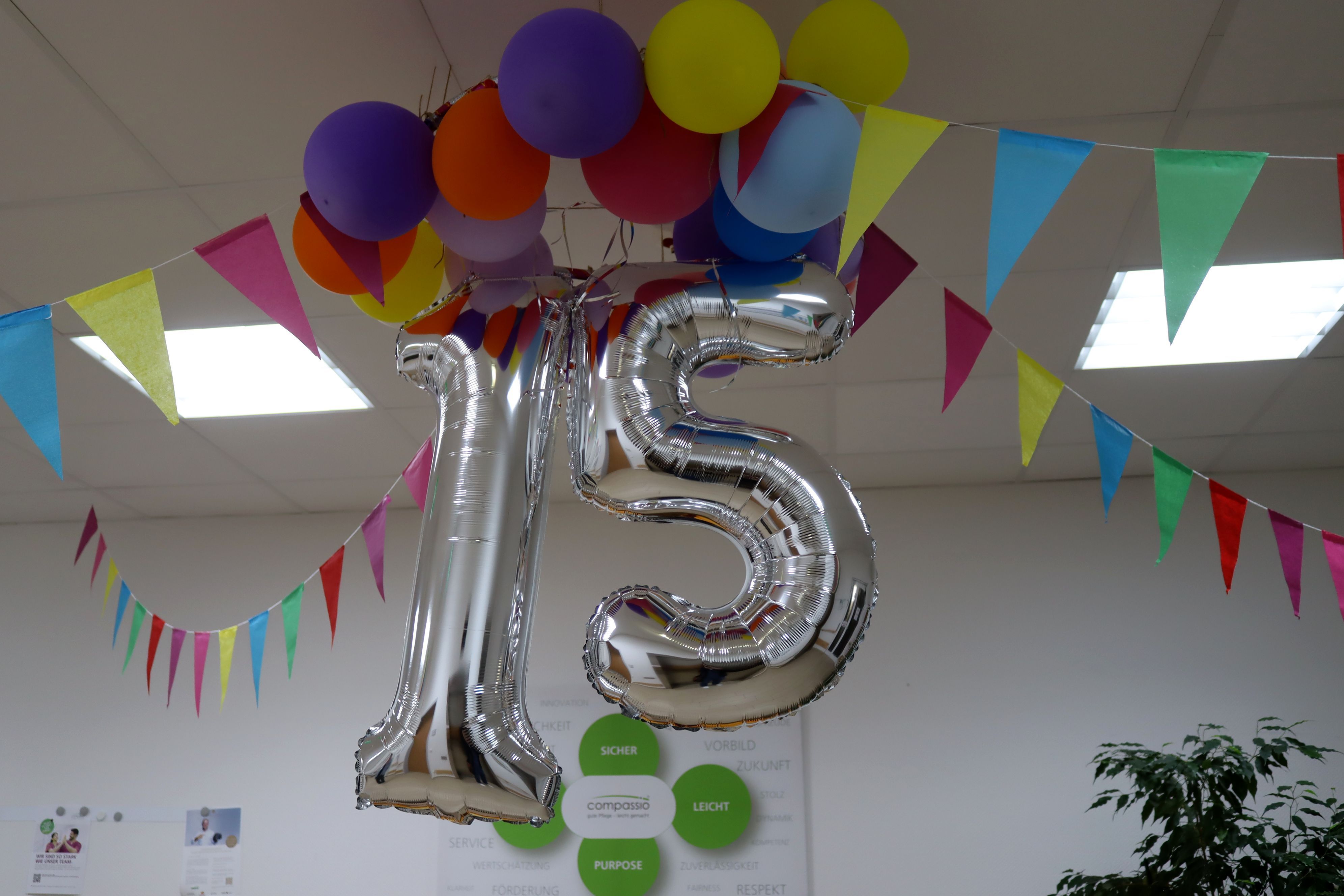 Bunte Luftballons und Girlanden sowie eine silberne 15 hängen im Eingangsbereich der Wohnanlage.
