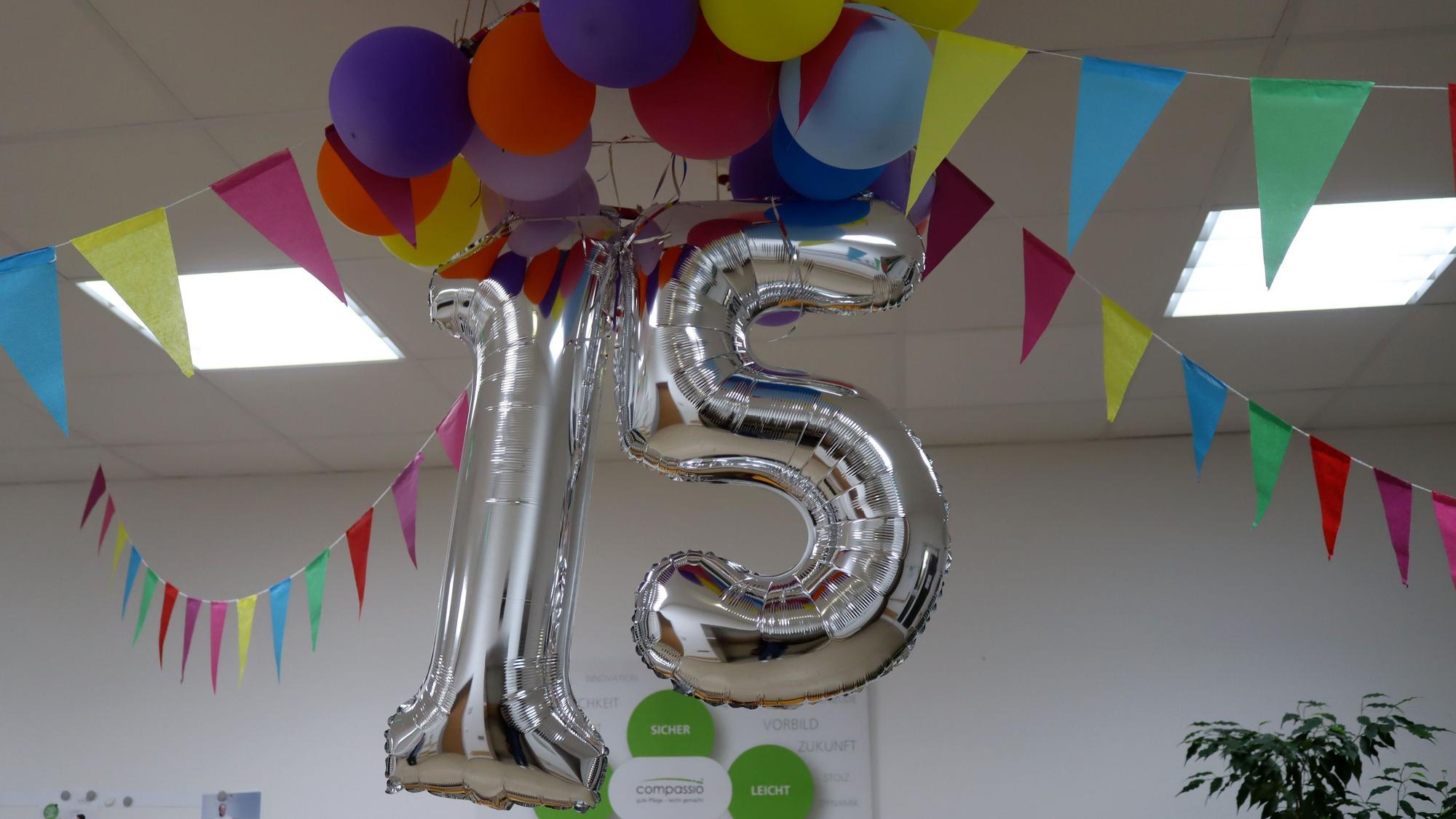 Bunte Luftballons und Girlanden sowie eine silberne 15 hängen im Eingangsbereich der Wohnanlage.