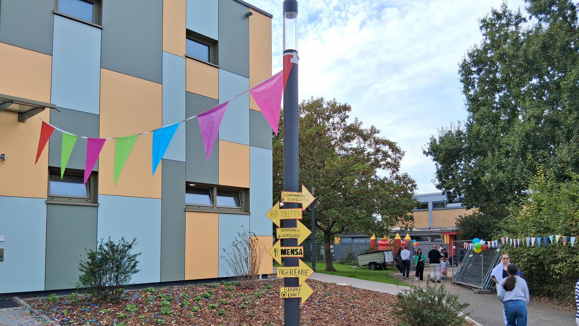 Vor einem Schulgebäude hängen bunte Wimpel.