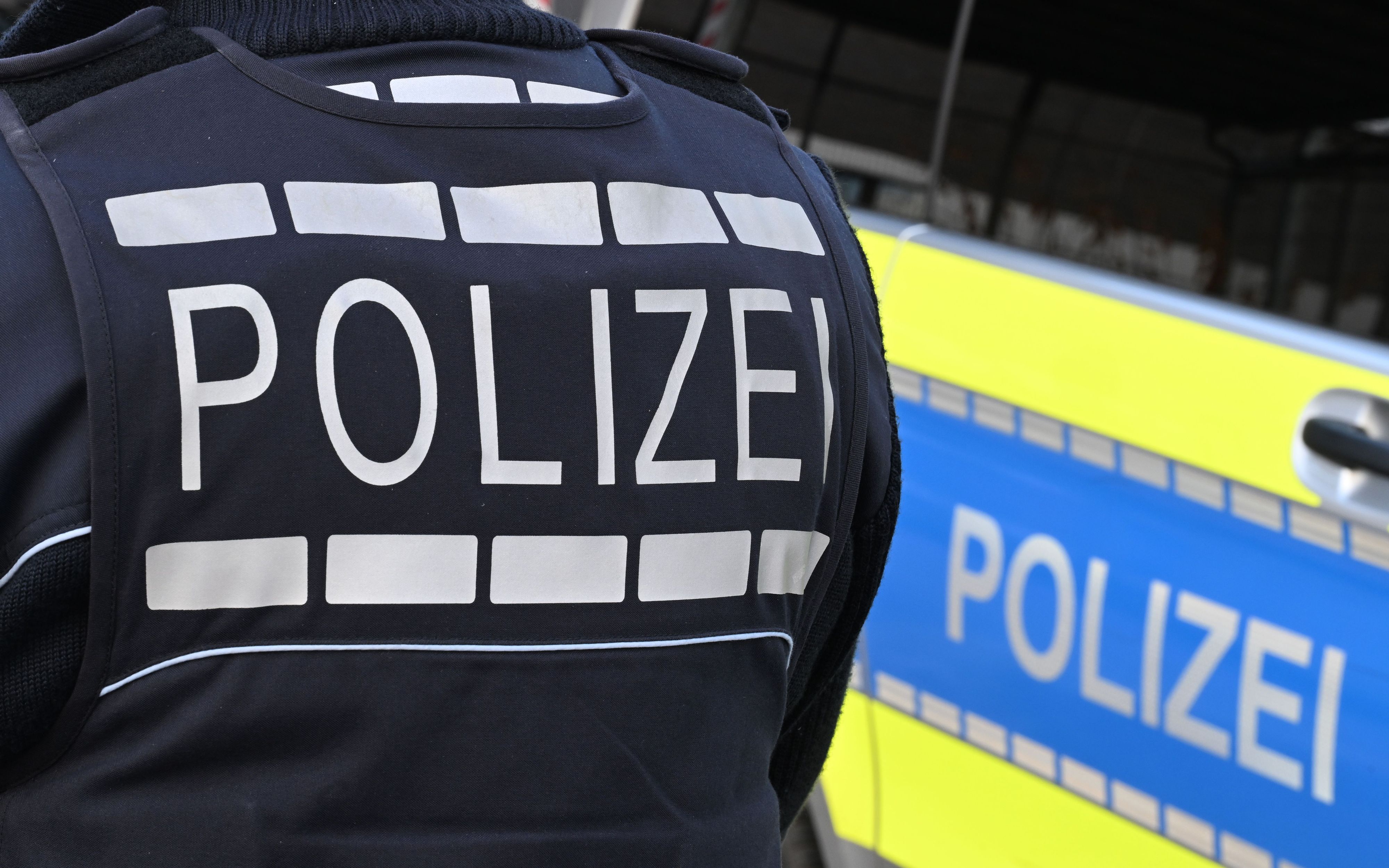Ein Polizist steht vor einem Auto der Polizei.