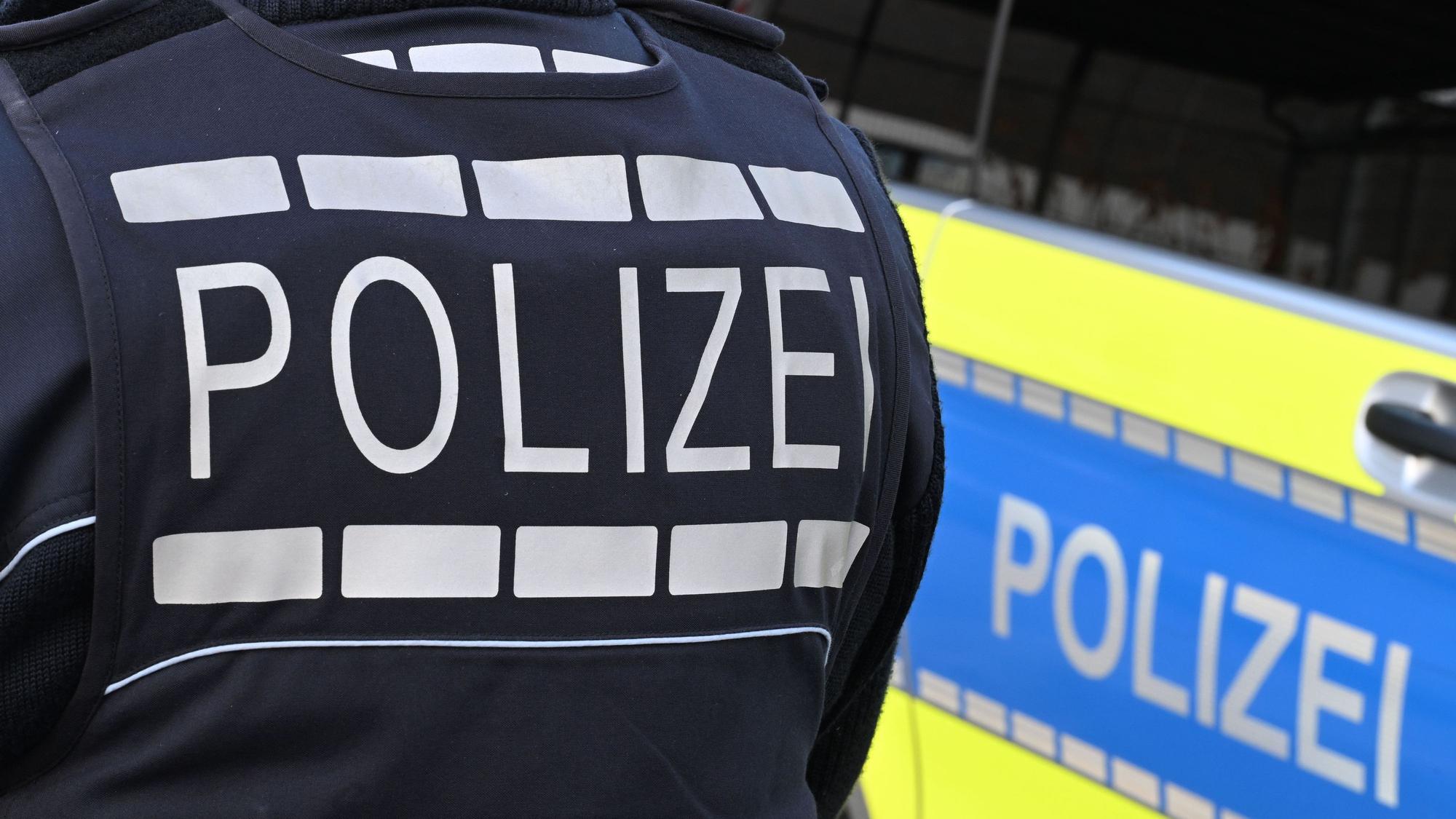 Ein Polizist steht vor einem Auto der Polizei.