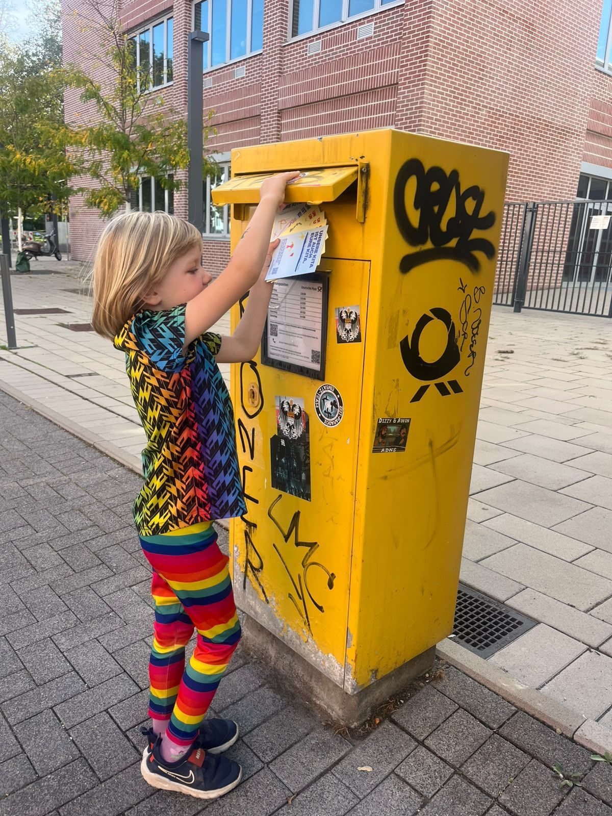 Ein Junge wirft eine Postkarte an ein Mitglied des Jugendhilfeausschusses in den Briefkasten