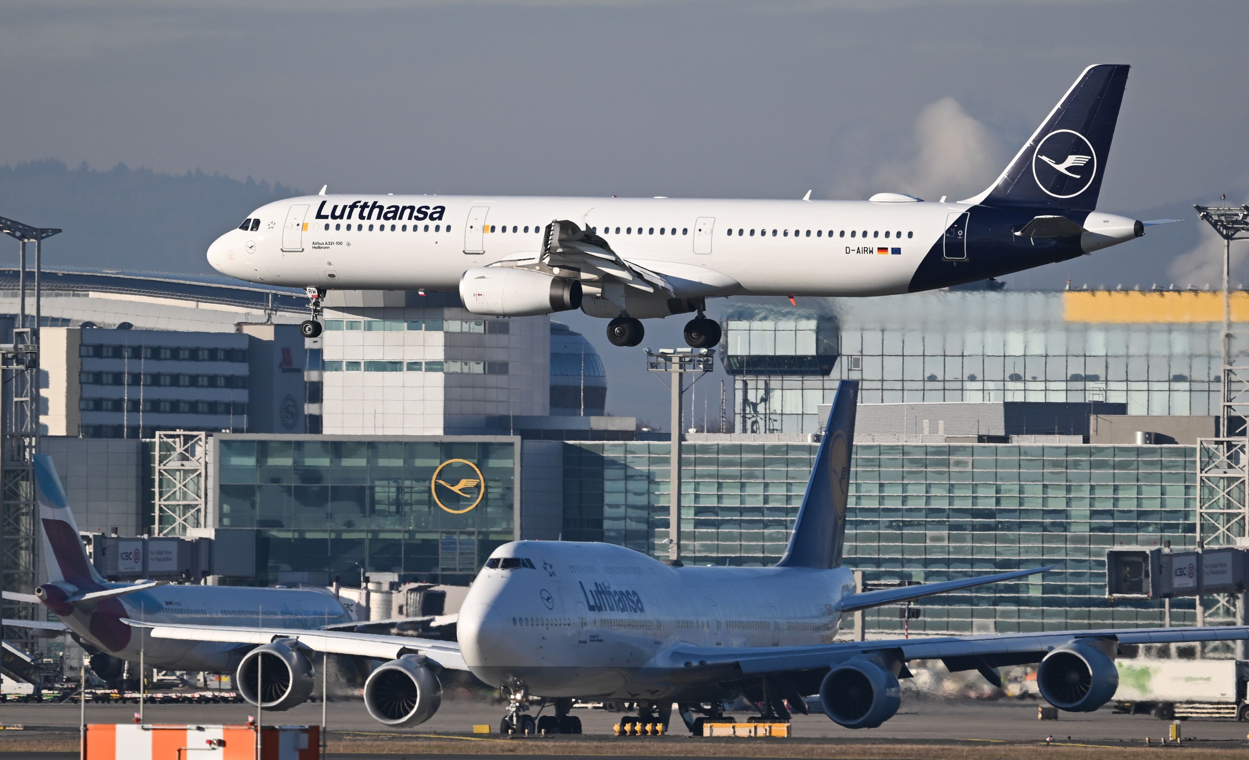 Ein Lufthansa Airbus A321-100 landet am Frankfurter Flughafen, während eine Lufthansa Boeing 747 vor der Startbahn warten muss.