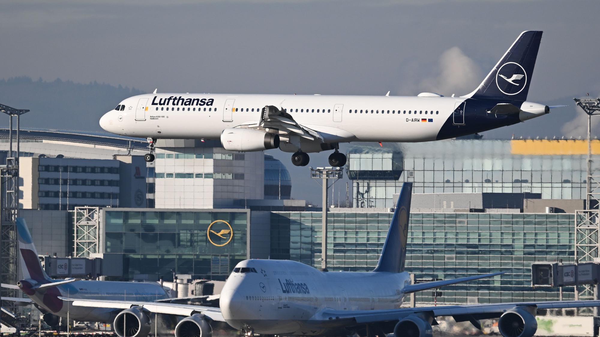 Ein Lufthansa Airbus A321-100 landet am Frankfurter Flughafen, während eine Lufthansa Boeing 747 vor der Startbahn warten muss.