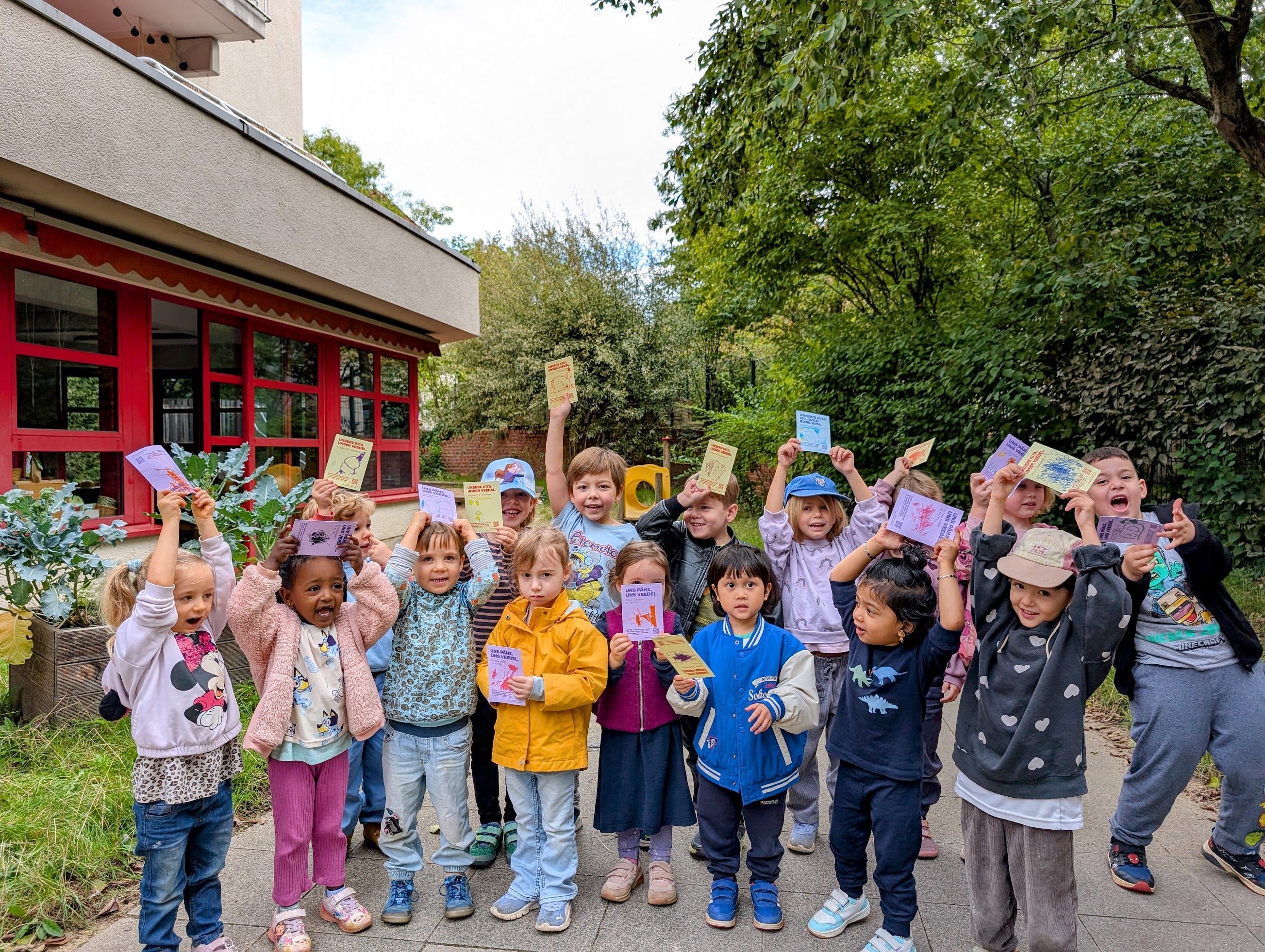 Die Kinder zeigen die Postkarten, die sie an Mitglieder des Jugendhilfausschusses geschrieben haben.