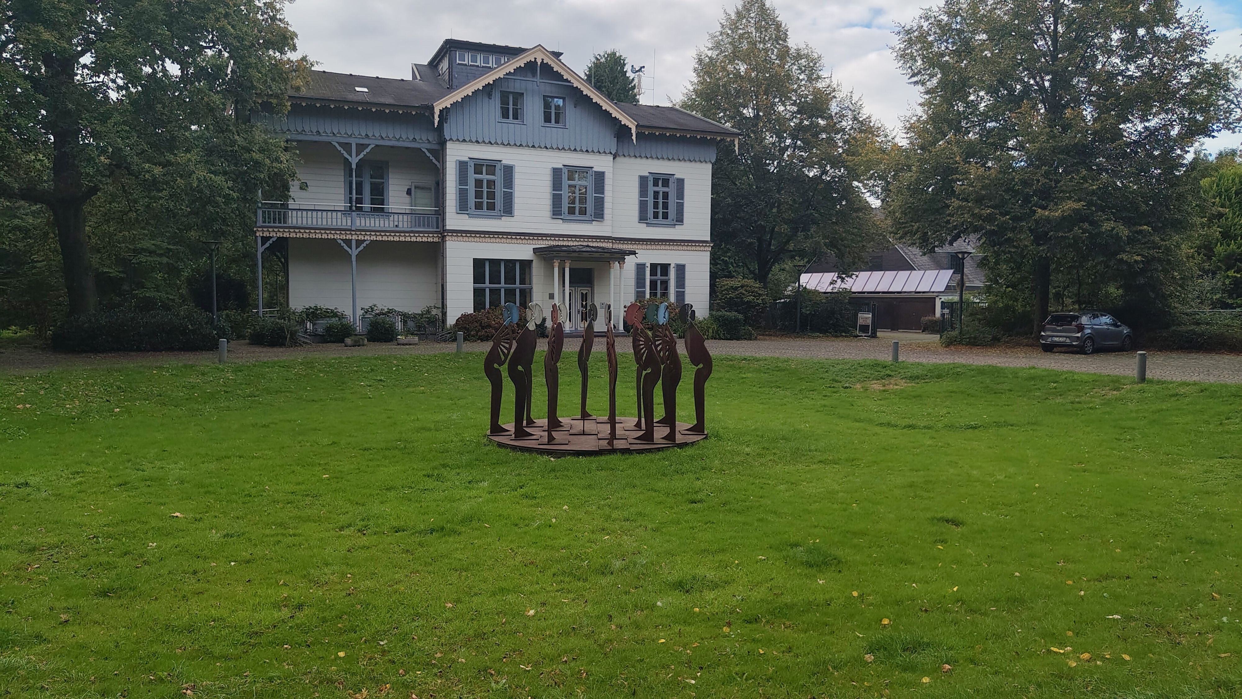 Es ist eine große Wiese mit der Villa Wuppermann zu sehen.