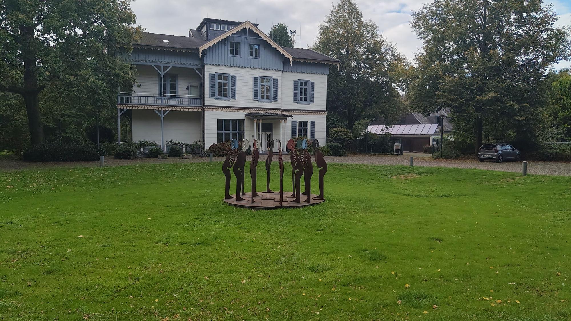 Es ist eine große Wiese mit der Villa Wuppermann zu sehen.
