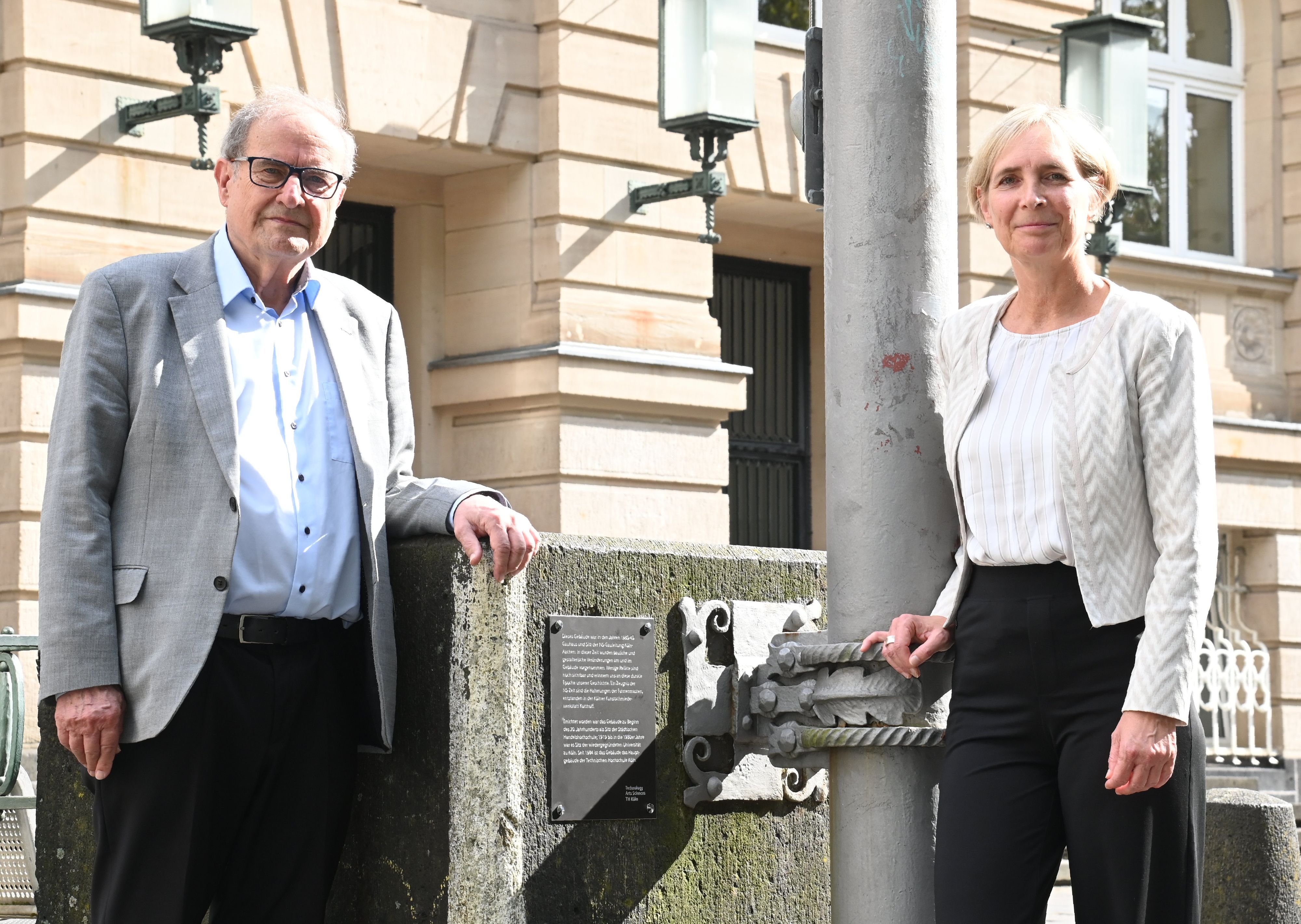 Die TH Köln hat eine Denkmalplakette in direktem Umfeld der Fahnenmasten installiert, um die Relikte der NS-Zeit sichtbar zu machen und historisch einzuordnen. Sylvia Heuchemer, Präsidentin der TH Köln, und Joachim Metzner, Präsident a.D. und Ehrensenator der TH Köln