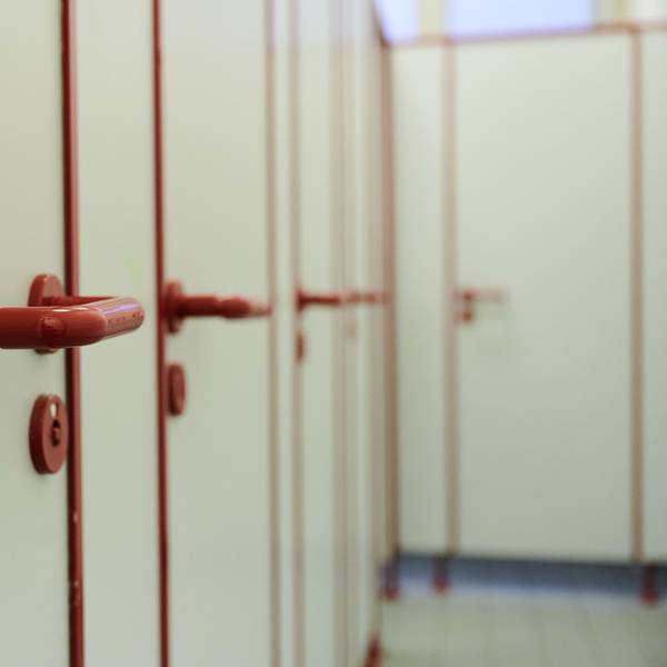 Die Türen mit roten griffen von Toiletten in einer Schule sind zu sehen.