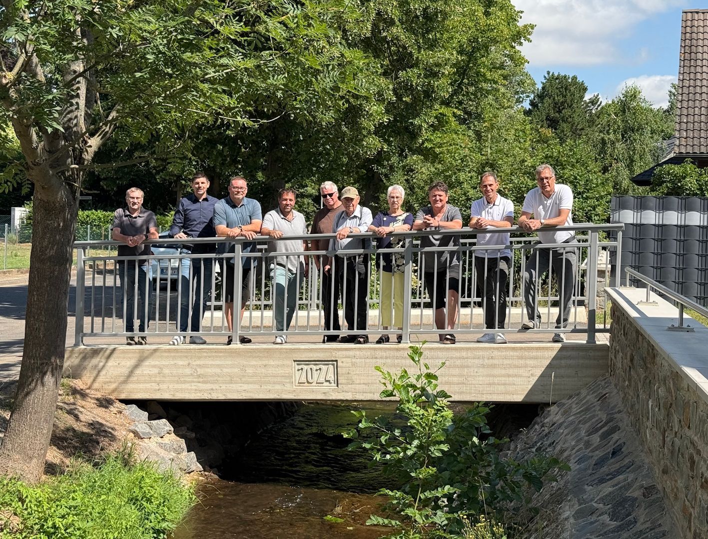 Eine Gruppe Menschen steht am Geländer einer neuen Brücke.