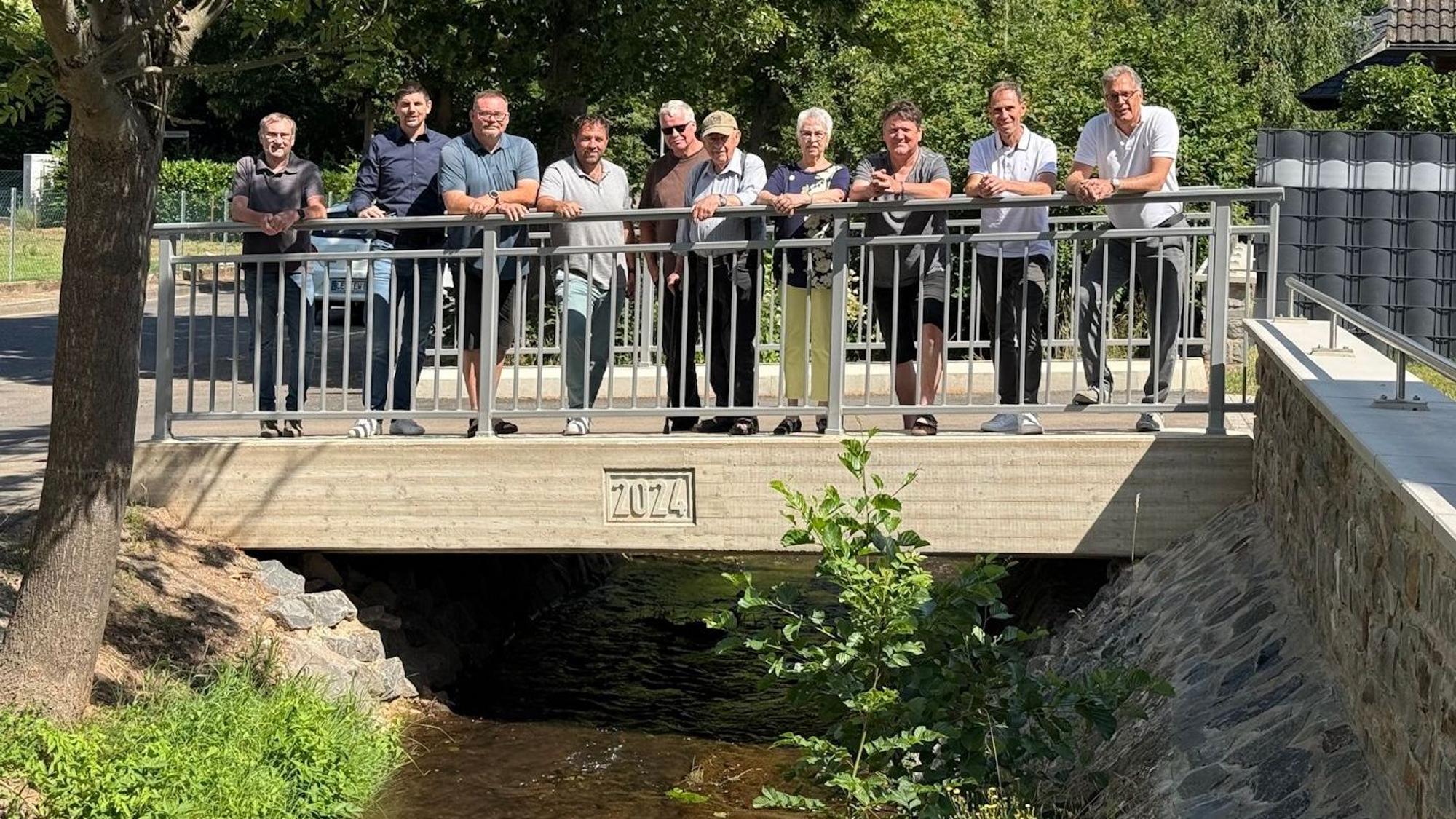Eine Gruppe Menschen steht am Geländer einer neuen Brücke.