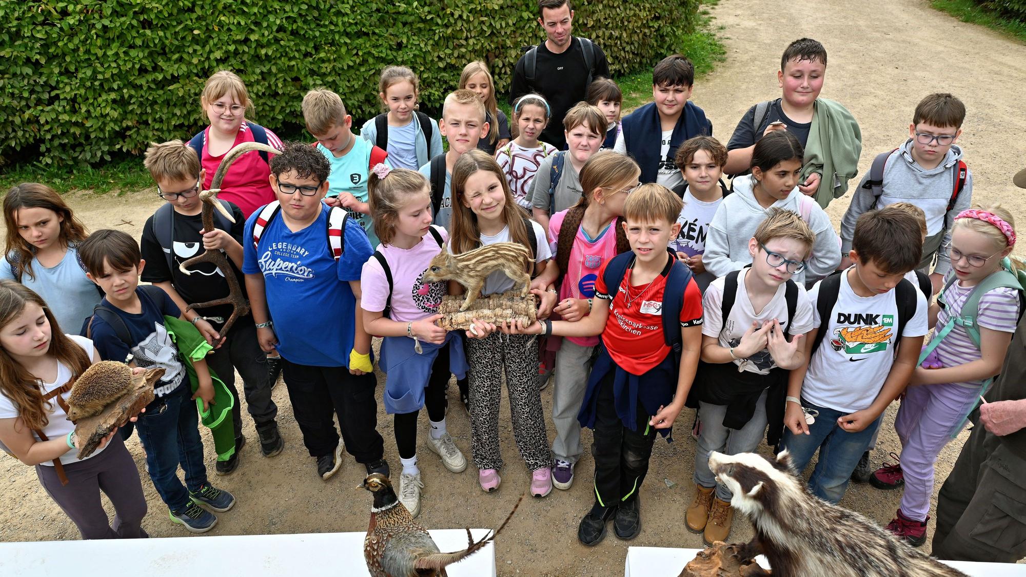 Einige der Kinder halten Tierpräparate in der Hand, etwa einen Igel und einen Frischling.