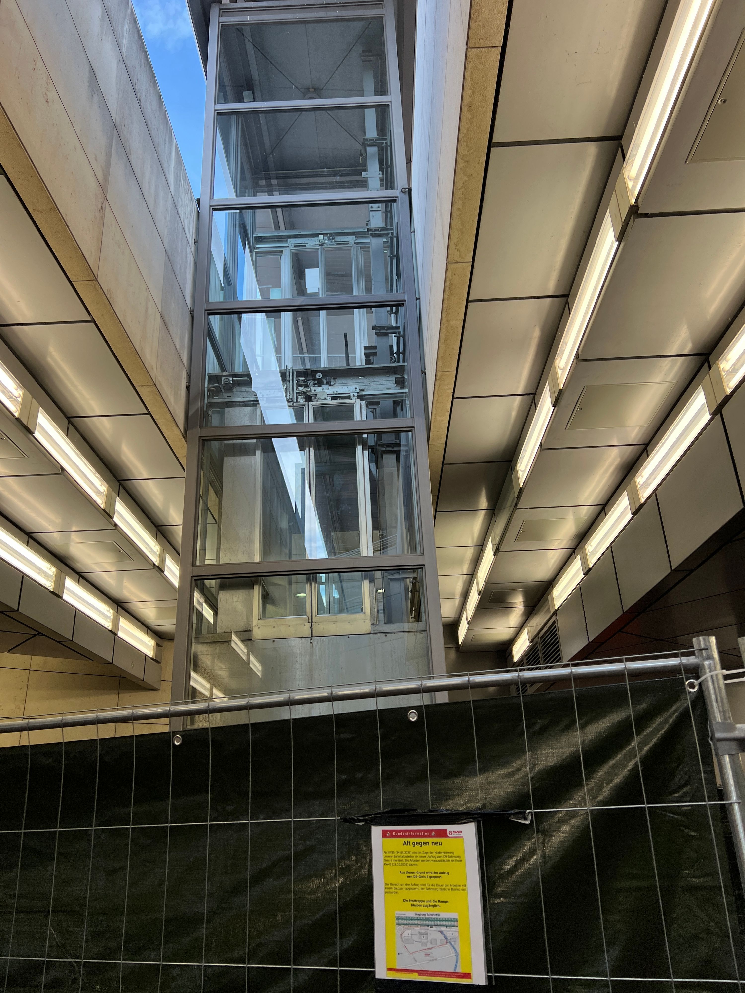 Seit Wochen gesperrt ist der Aufzug zum Gleis 6, wo die ICE nach Frankfurt abfahren. Inzwischen passiert etwas: Hinter einem neu eingezogenen Sichtschutz montieren Mitarbeiter eines kroatischen Spezialunternehmens einen neuen Lift.