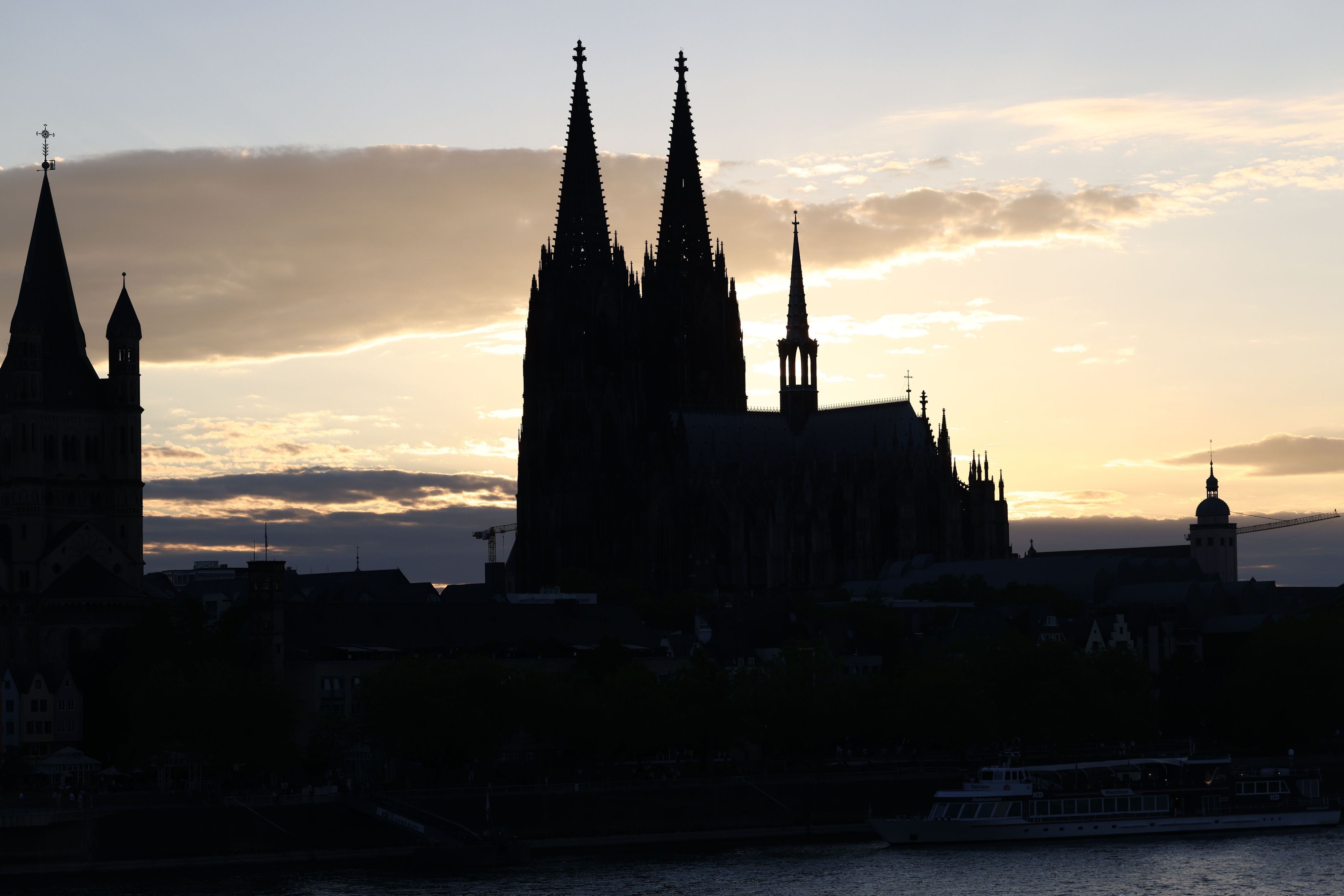 Der Kölner Dom zeichnet sich als Silhouette vor der untergehenden Sonne ab.