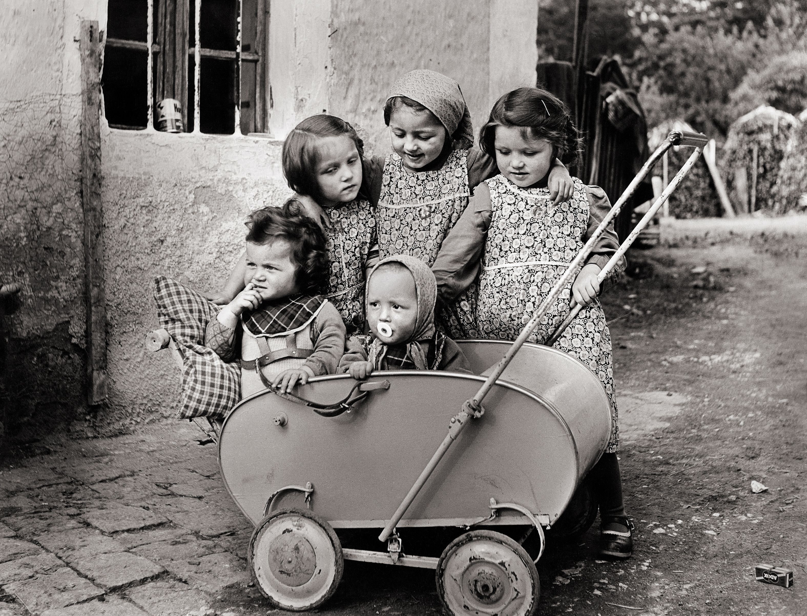 Fünf Mädchen stehen um einen Kinderwagen herum.