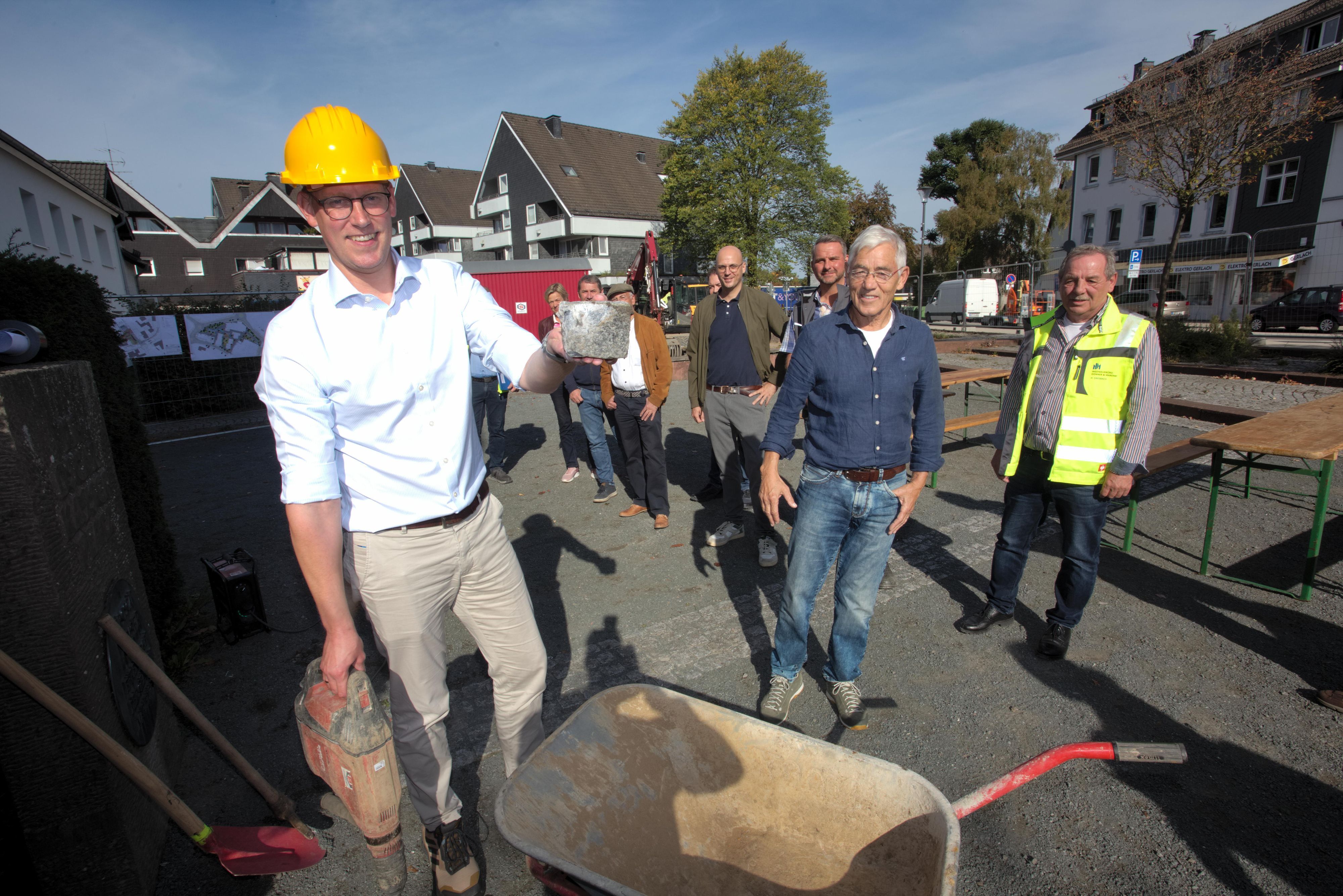 Das Foto zeigt Bürgermeister Sebastian Heimes (l.) mit einem Granitstein, der später wieder verwendet werden soll.
