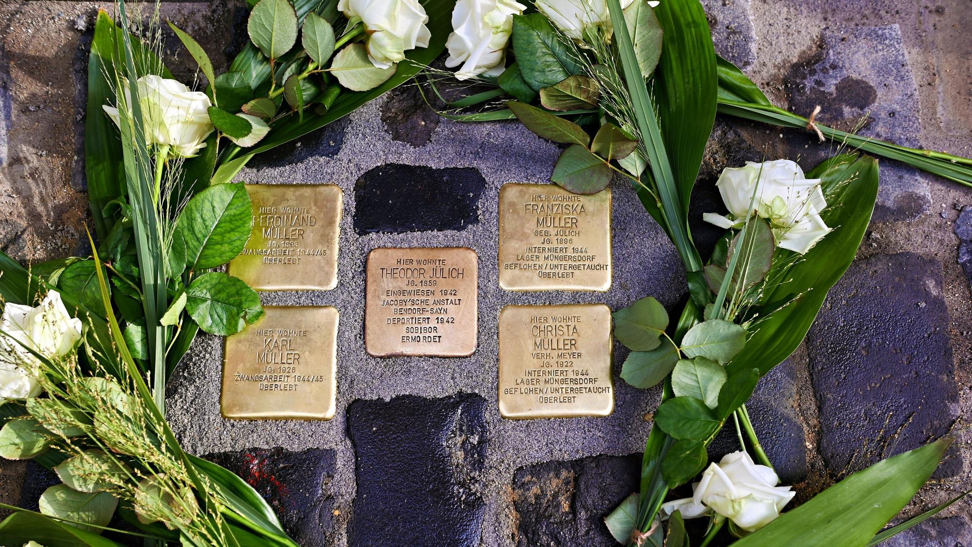 Die Stolpersteine sind von weißen Rosen umgeben.