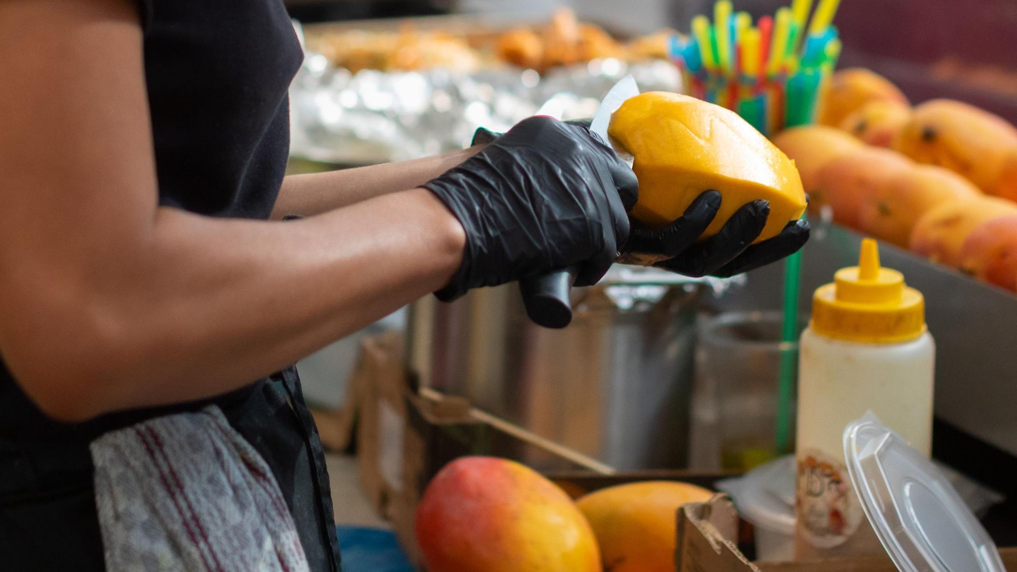 Eine Person schält eine Mango.